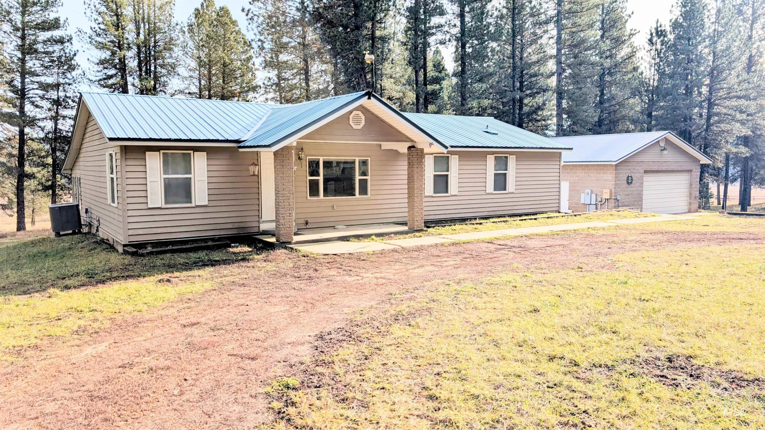 Single story home with a metal roof, a garage, and a front lawn