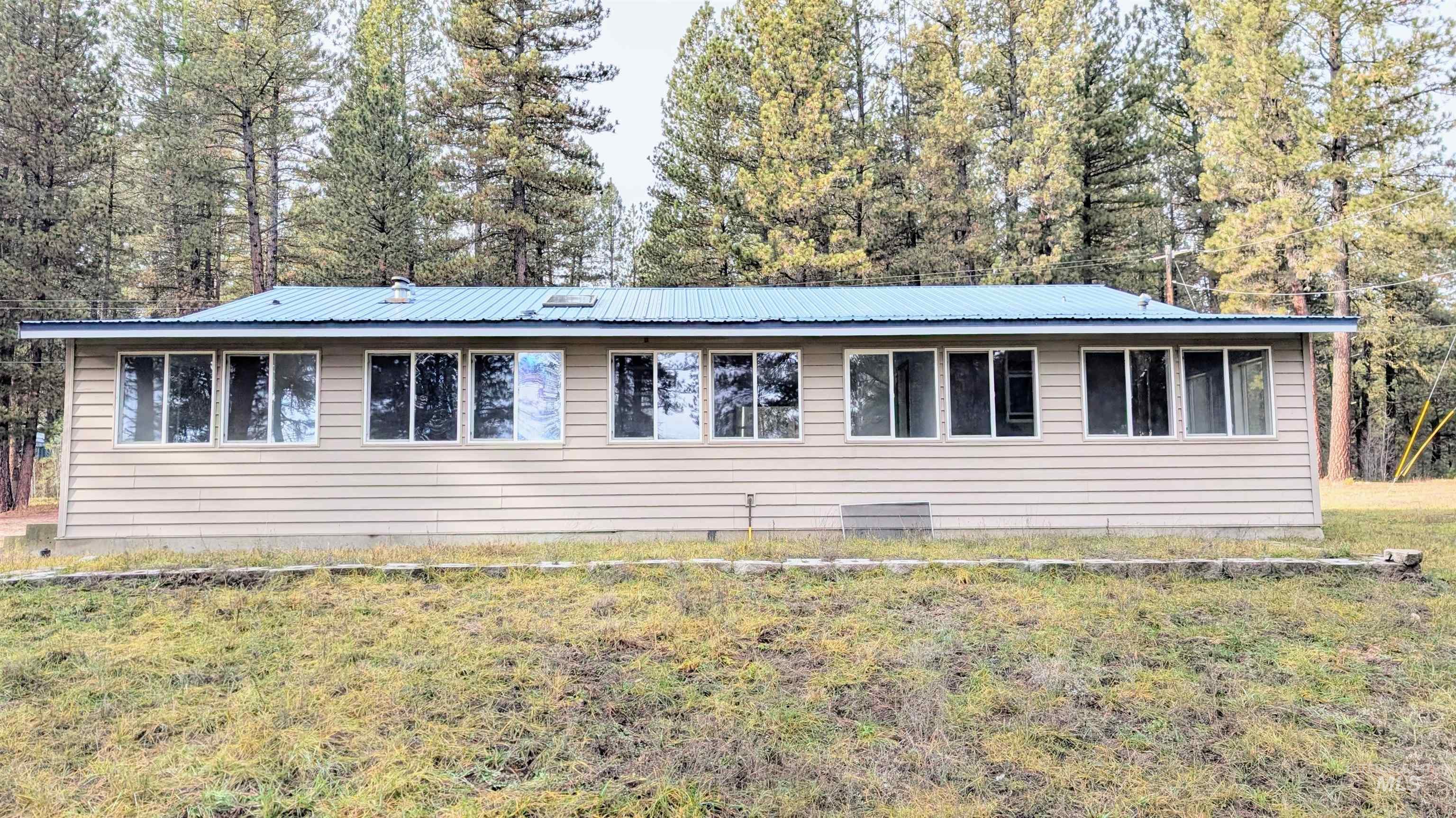 View of front facade featuring a front lawn and a metal roof