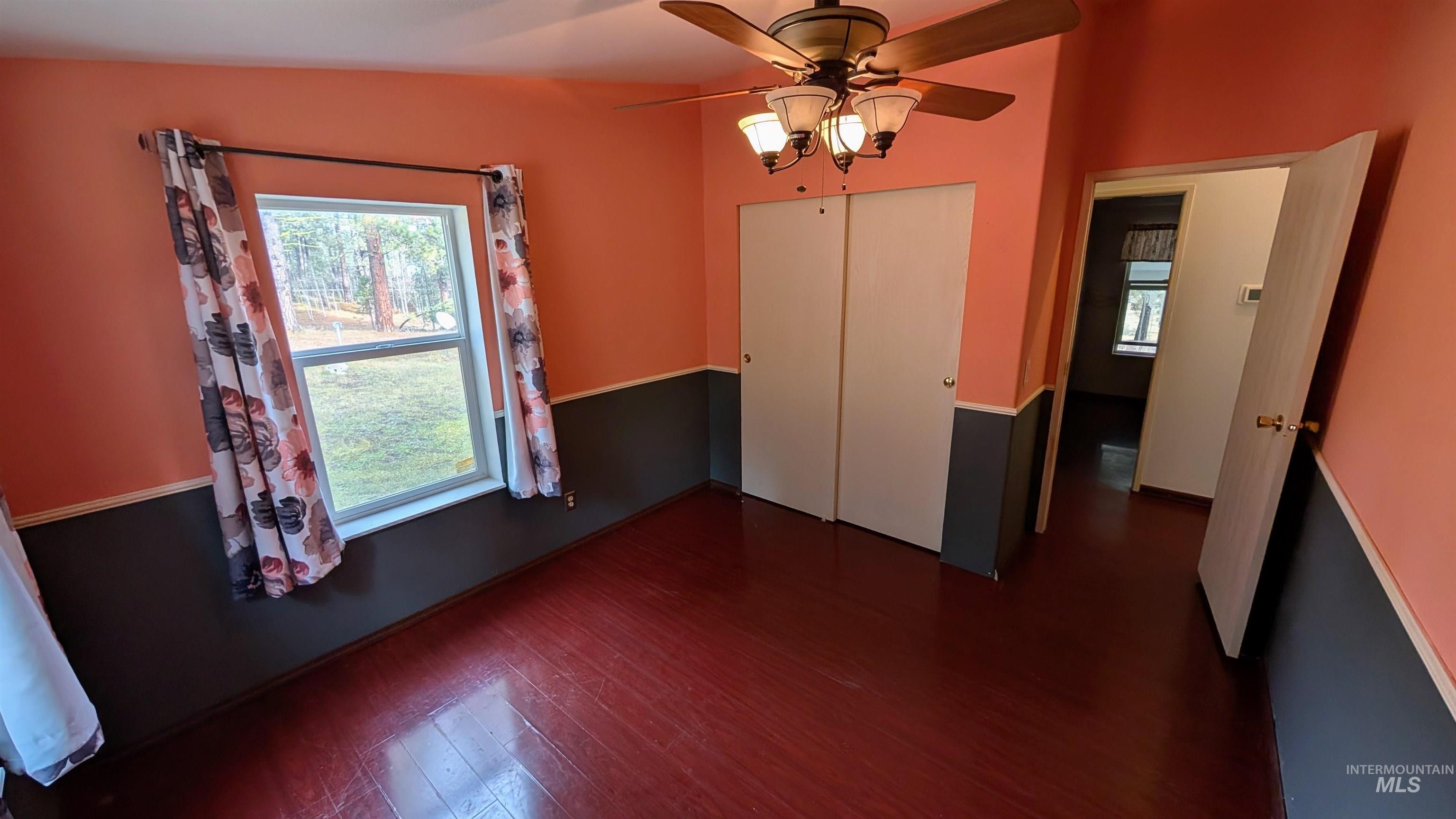 Unfurnished dining area with plenty of natural light, dark wood-style floors, and a ceiling fan