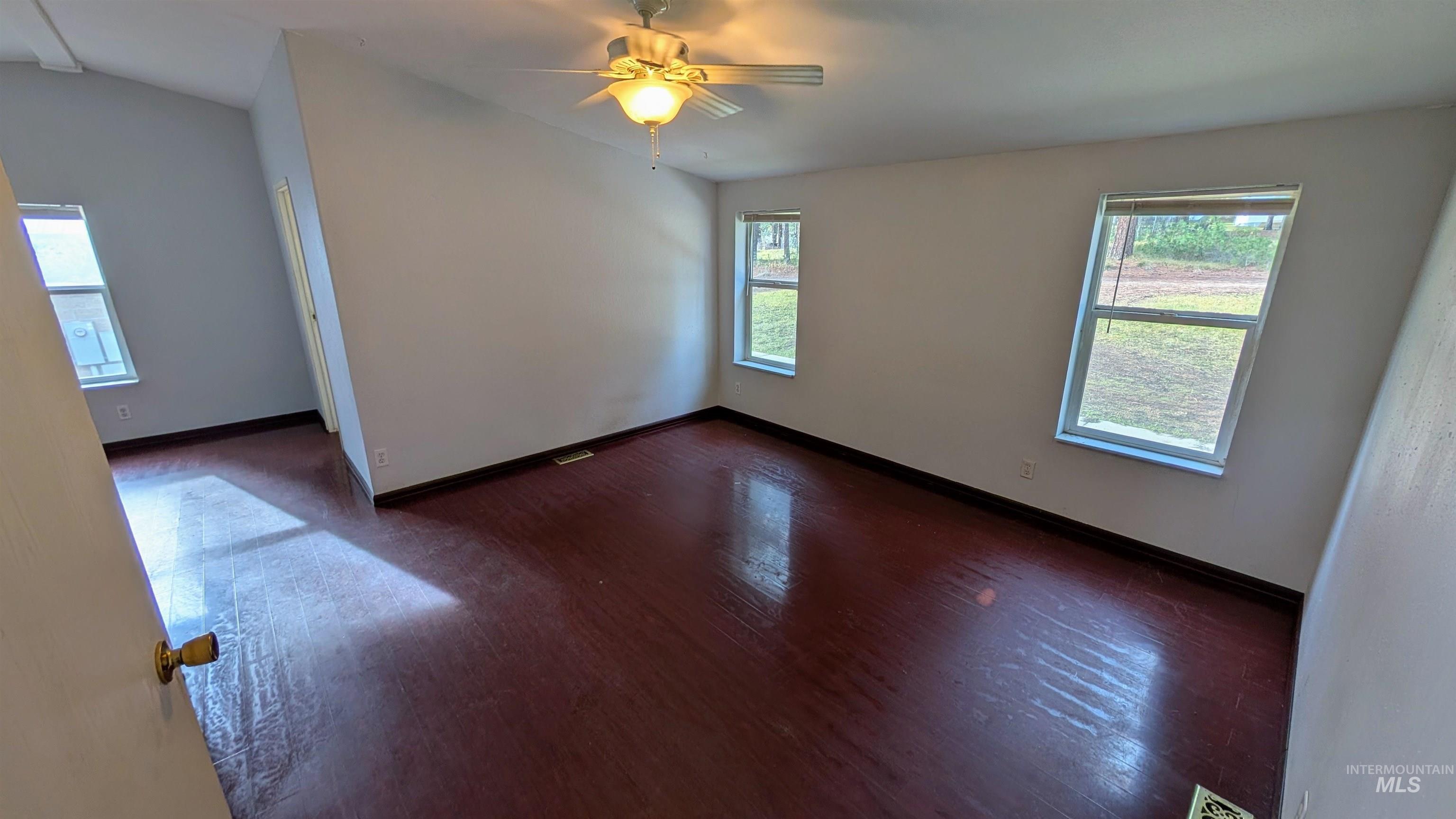 Empty room featuring dark wood-type flooring and ceiling fan