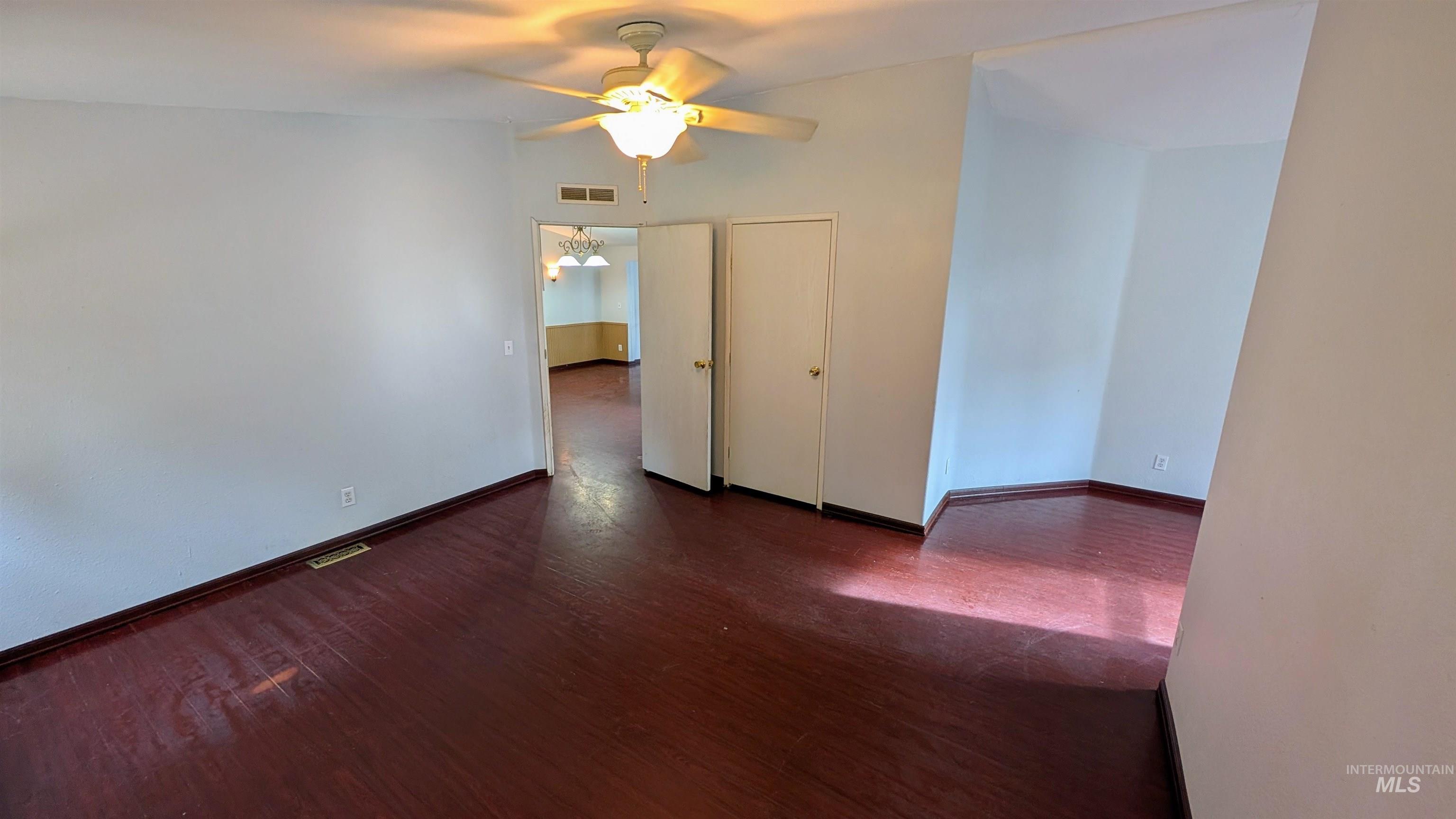 Empty room featuring dark wood-style flooring and ceiling fan