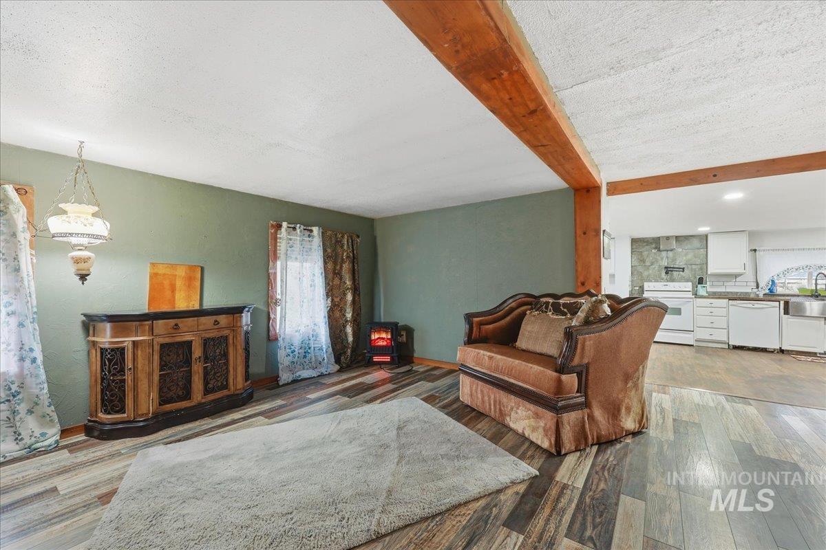 Living area with beam ceiling, a textured ceiling, and light wood-style floors