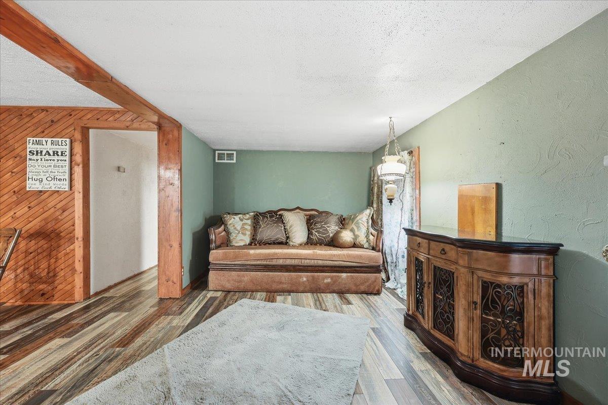 Living area featuring wood finished floors, a textured ceiling, and wooden walls