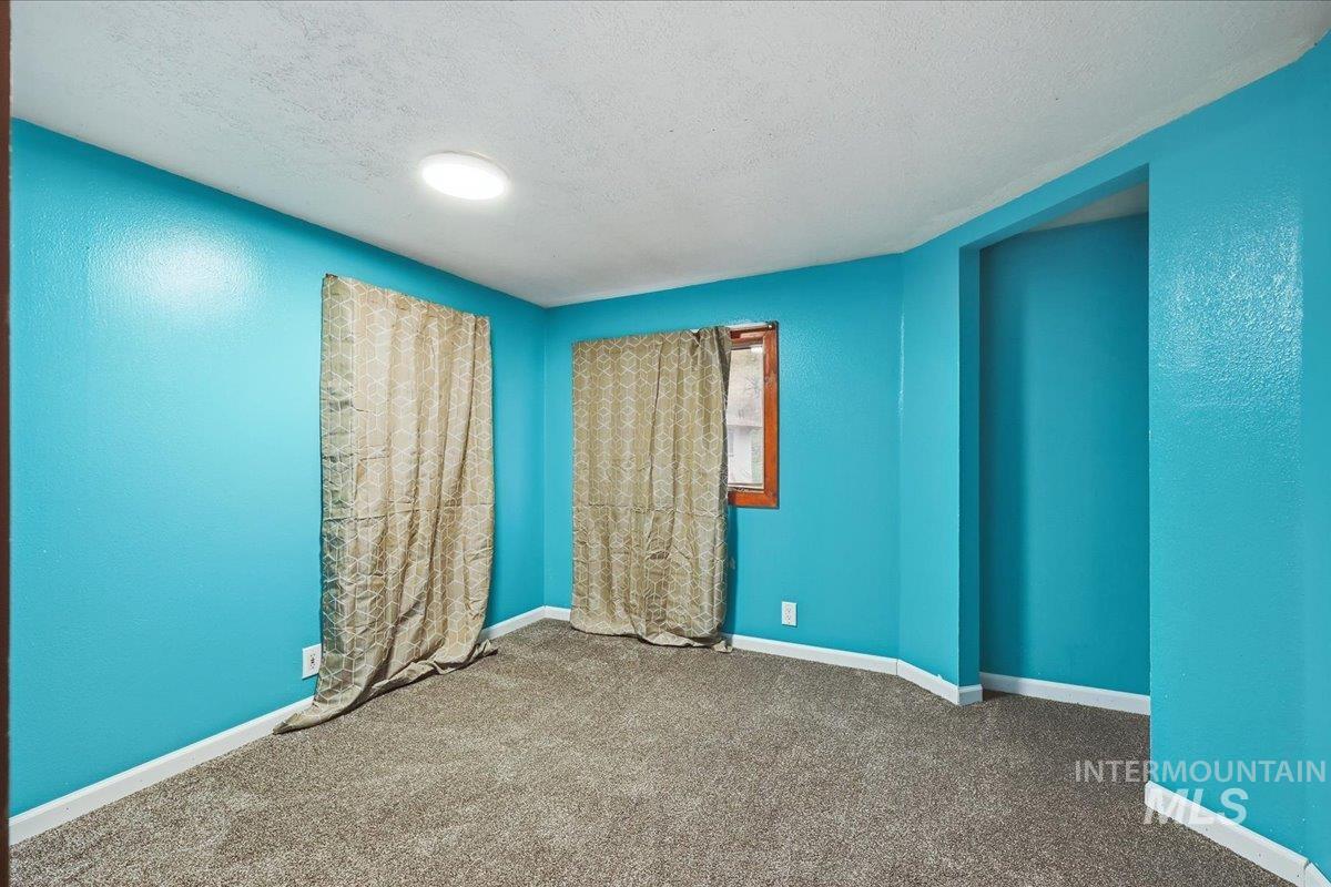 Spare room featuring a textured ceiling, carpet flooring, and a textured wall