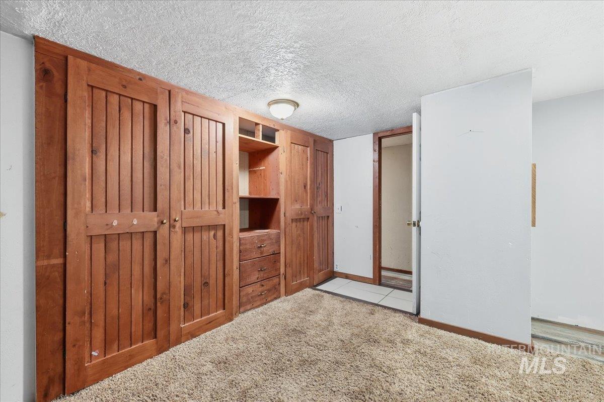 Unfurnished bedroom featuring a textured ceiling and light colored carpet