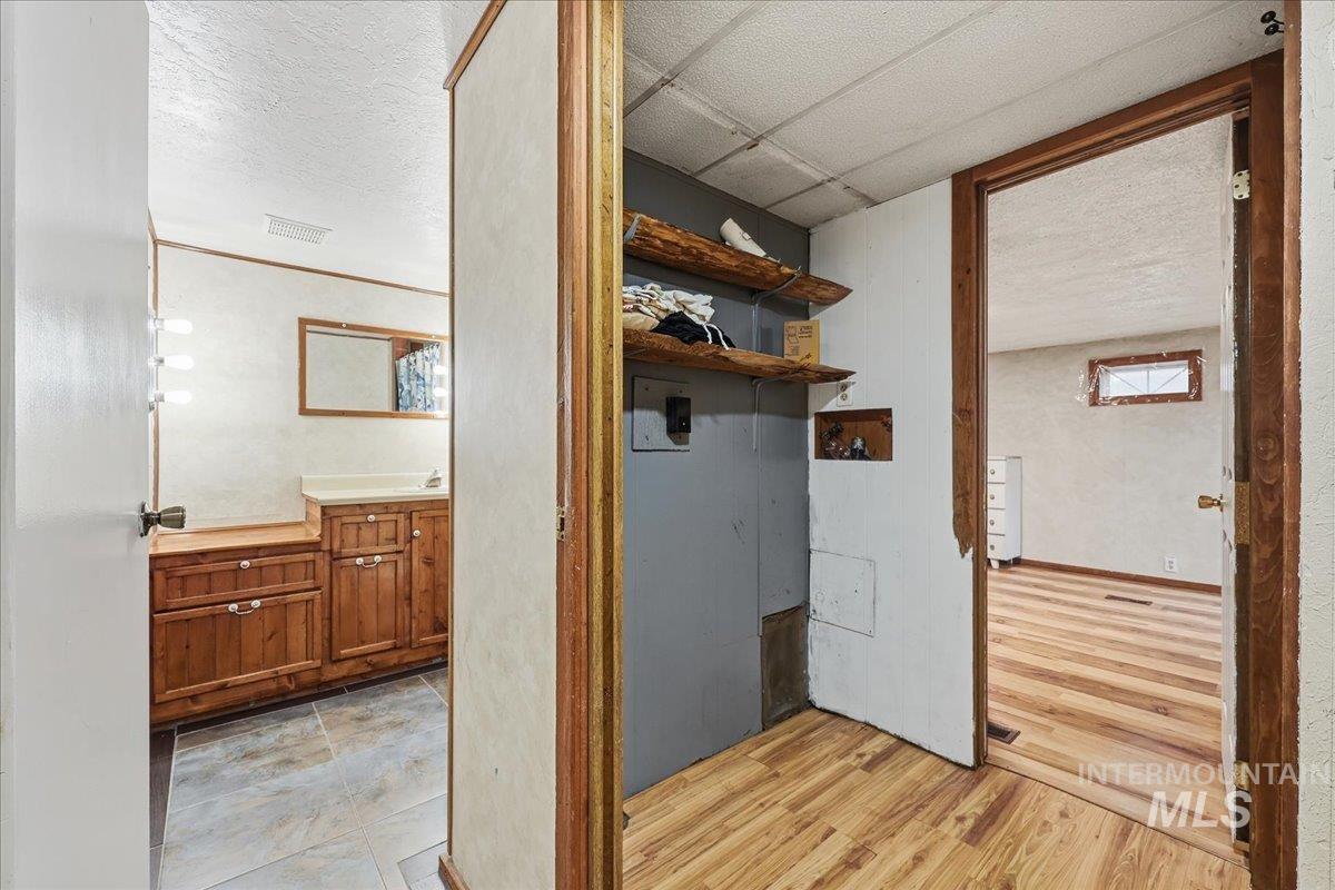 Laundry area with a textured ceiling and light wood finished floors
