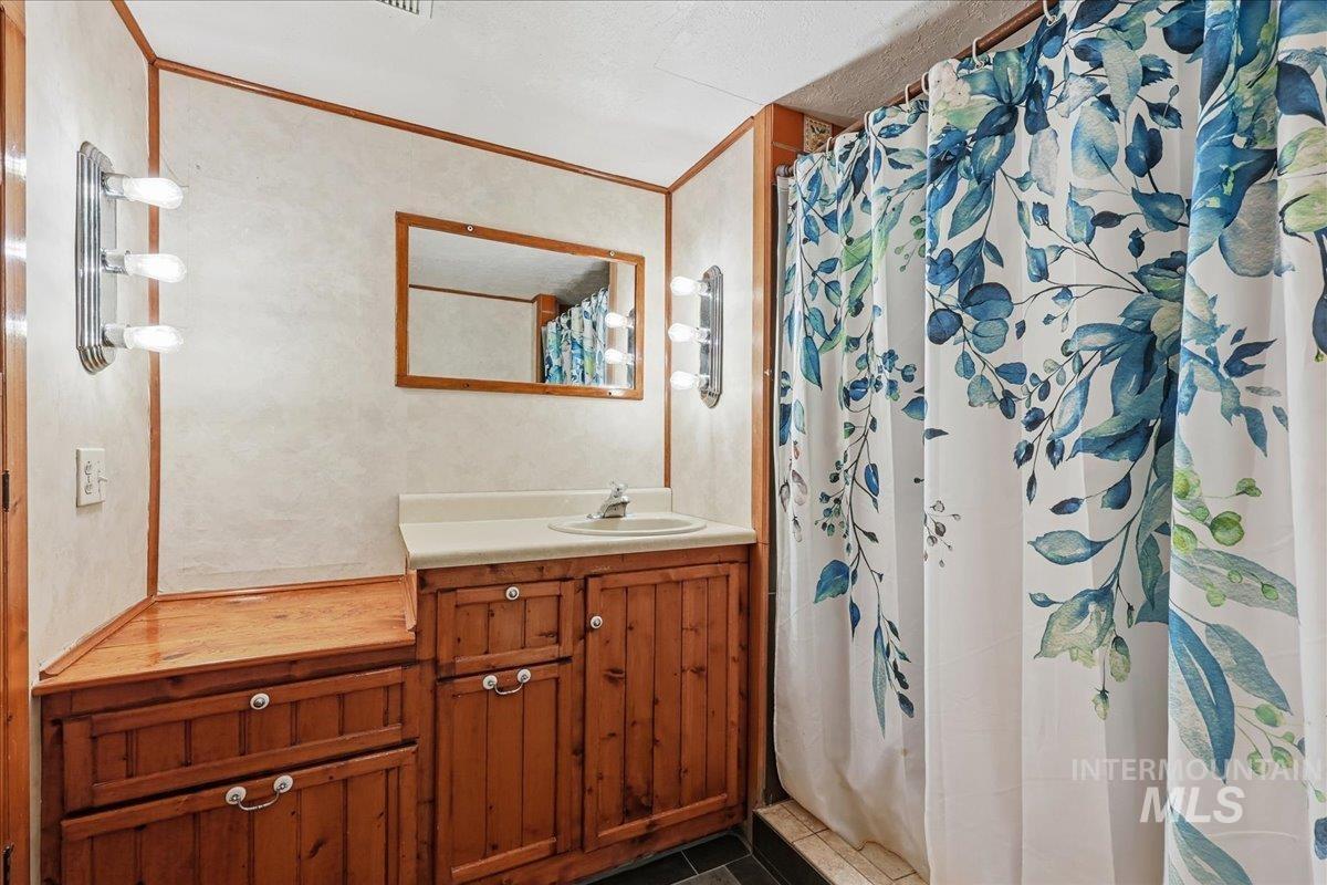 Full bathroom featuring vanity, a shower with curtain, crown molding, and tile patterned floors