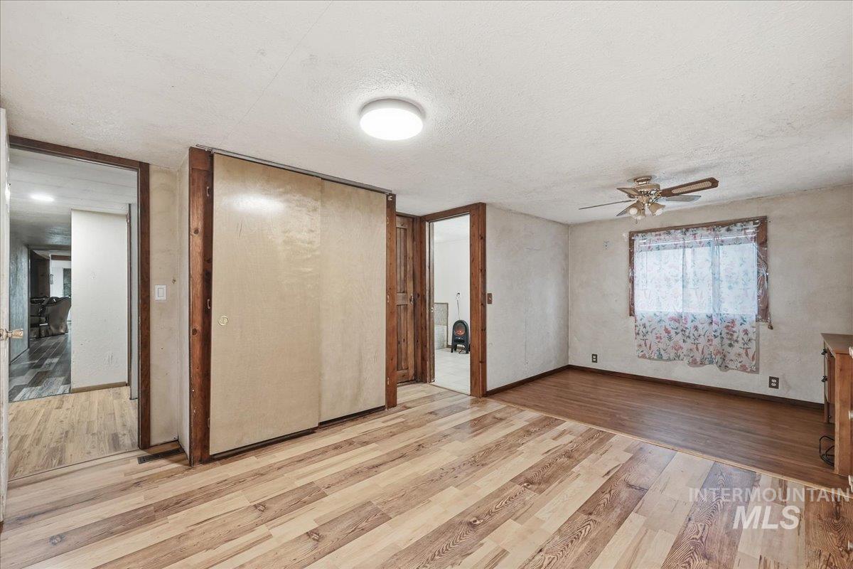Unfurnished bedroom featuring light wood finished floors, a textured ceiling, a closet, and a ceiling fan