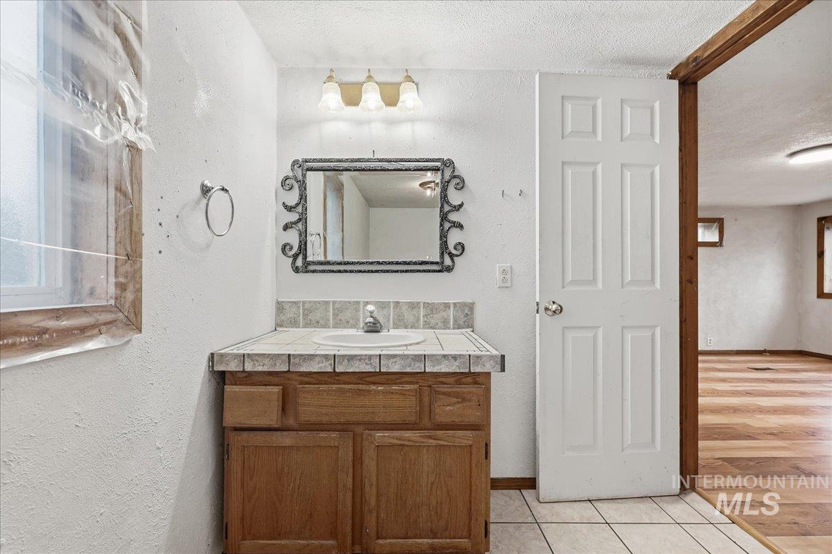 Bathroom featuring a textured wall, vanity, a textured ceiling, and light tile patterned floors