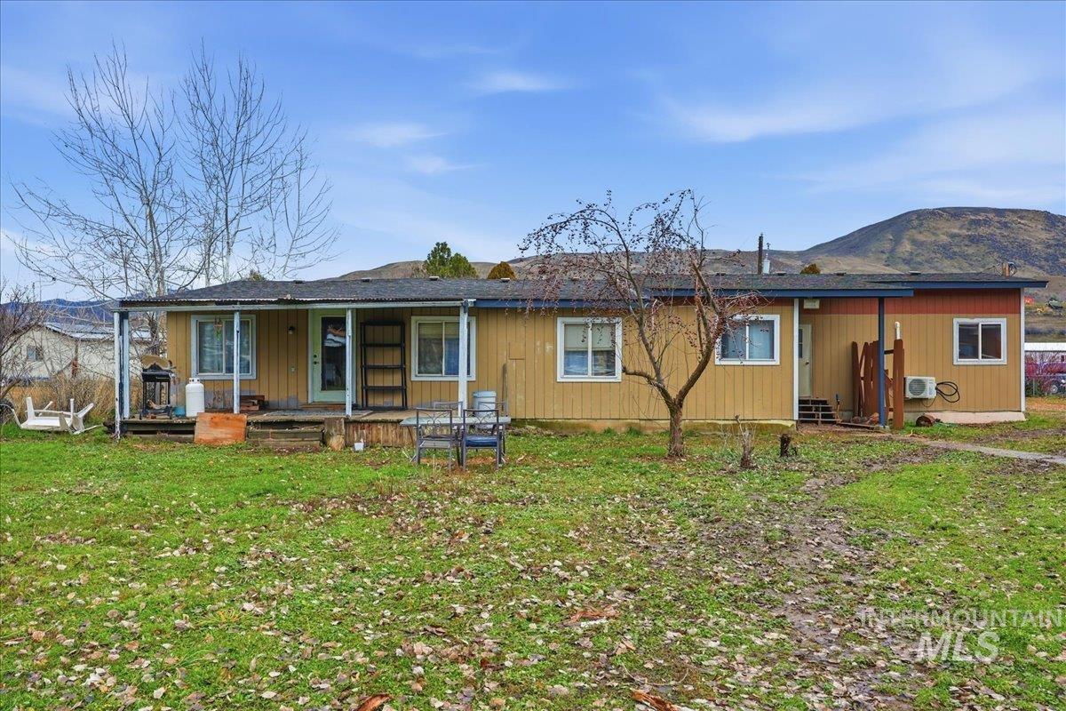 Back of house featuring a lawn, covered porch, and a mountain view