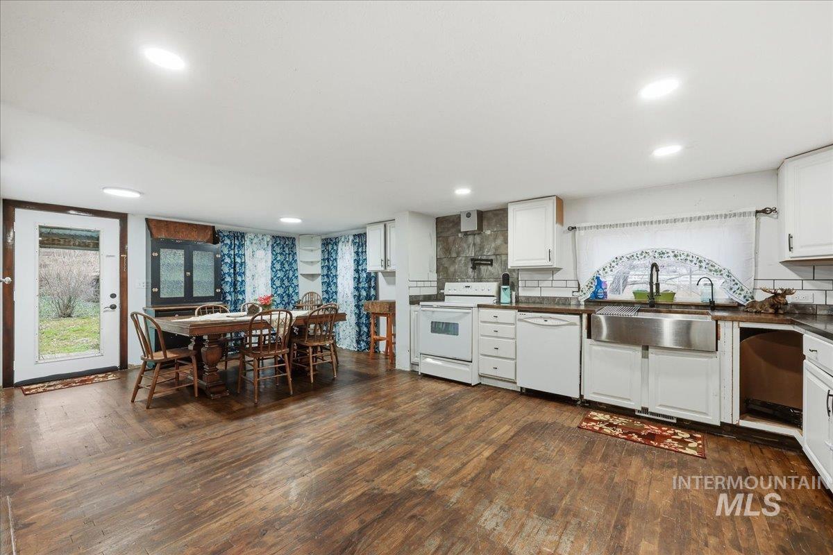 Kitchen with white cabinetry, white appliances, dark wood-style flooring, and decorative backsplash