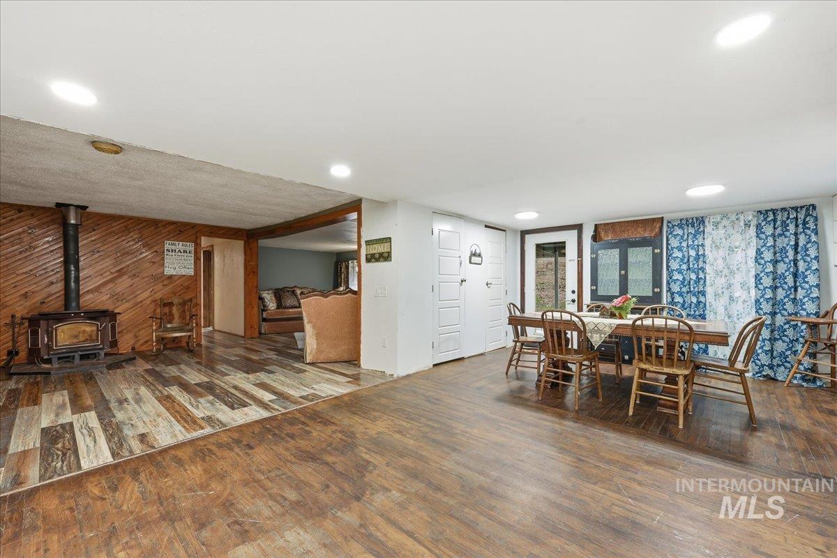 Dining area with hardwood / wood-style flooring, a wood stove, wood walls, and recessed lighting