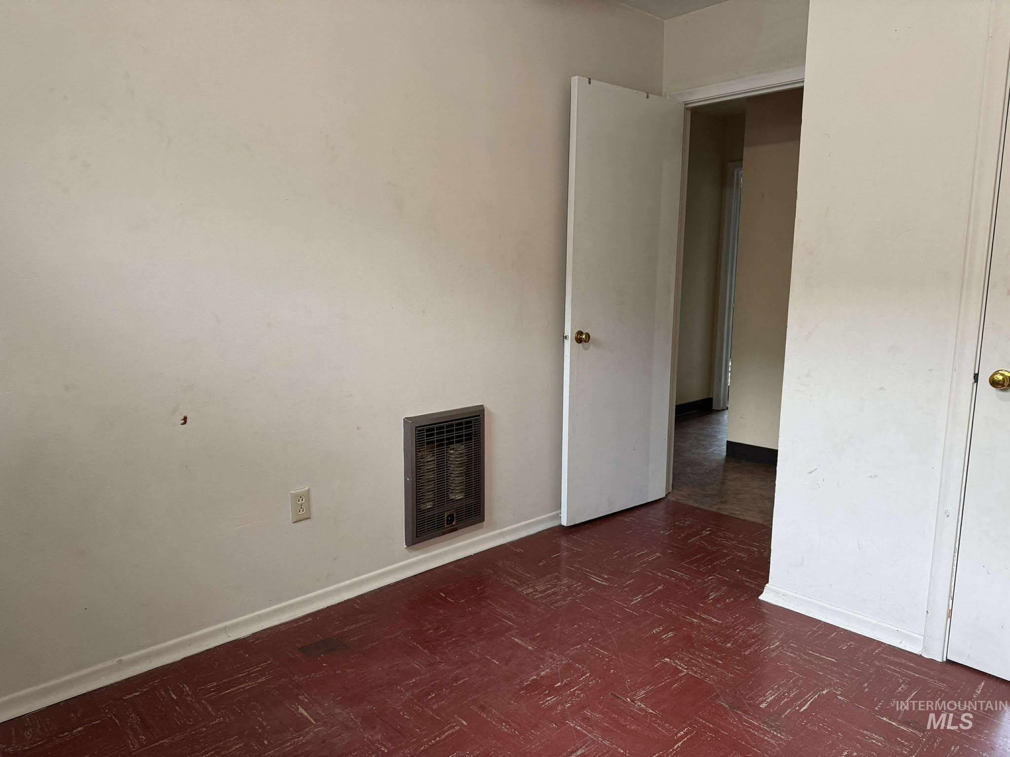 Unfurnished bedroom featuring heating unit and dark floors