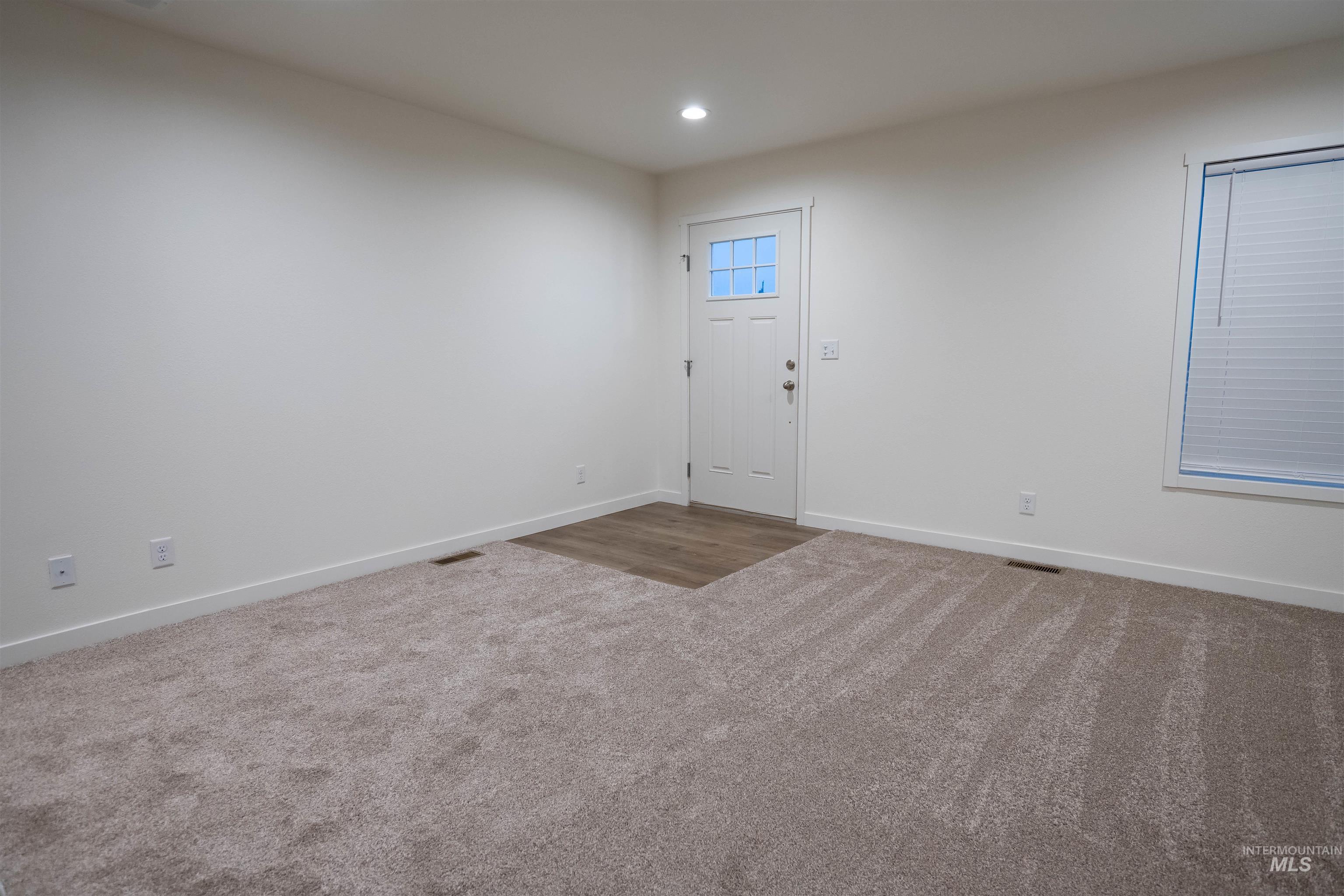 Carpeted foyer entrance with baseboards and recessed lighting