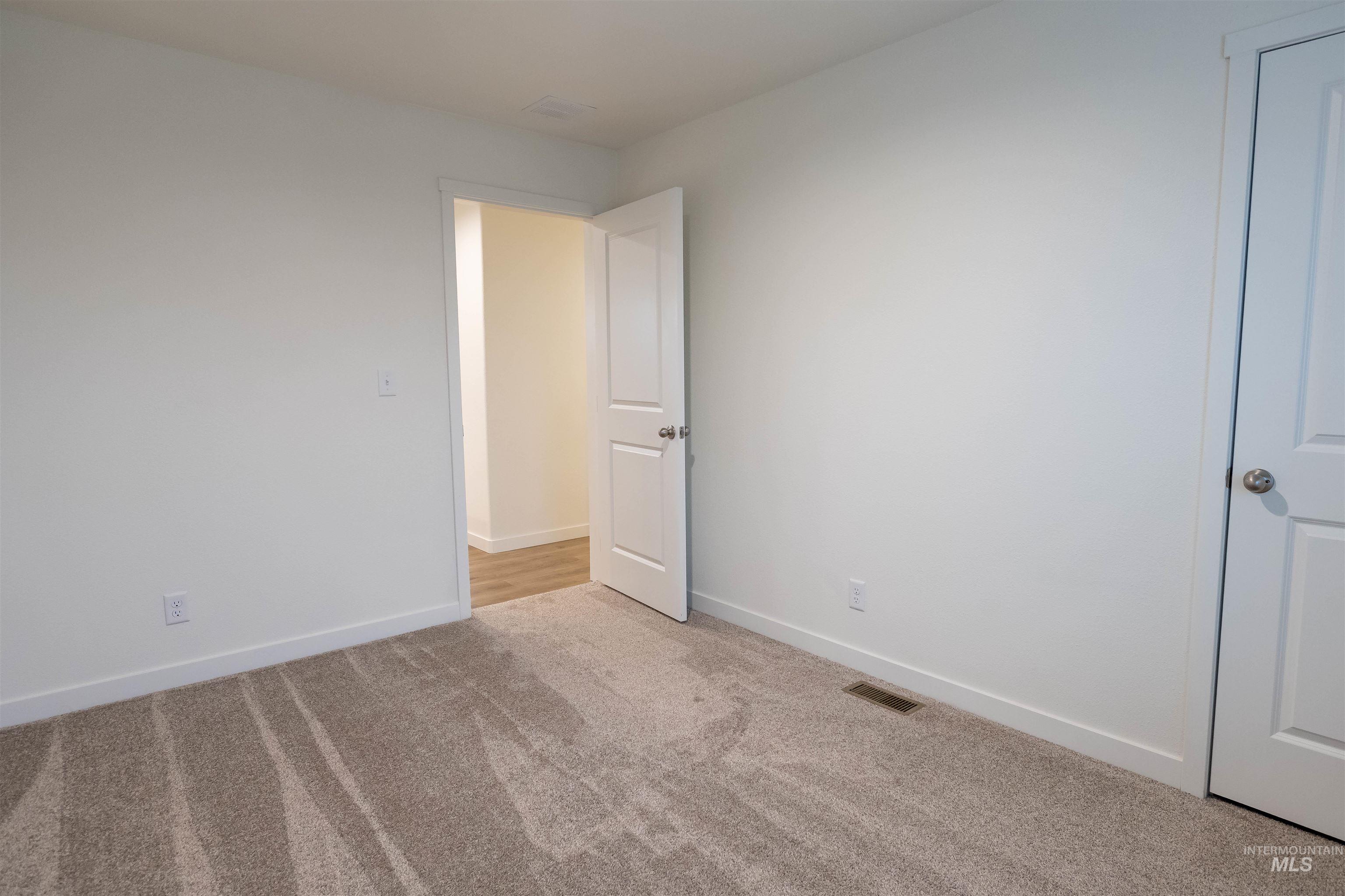 Unfurnished room with baseboards and light carpet