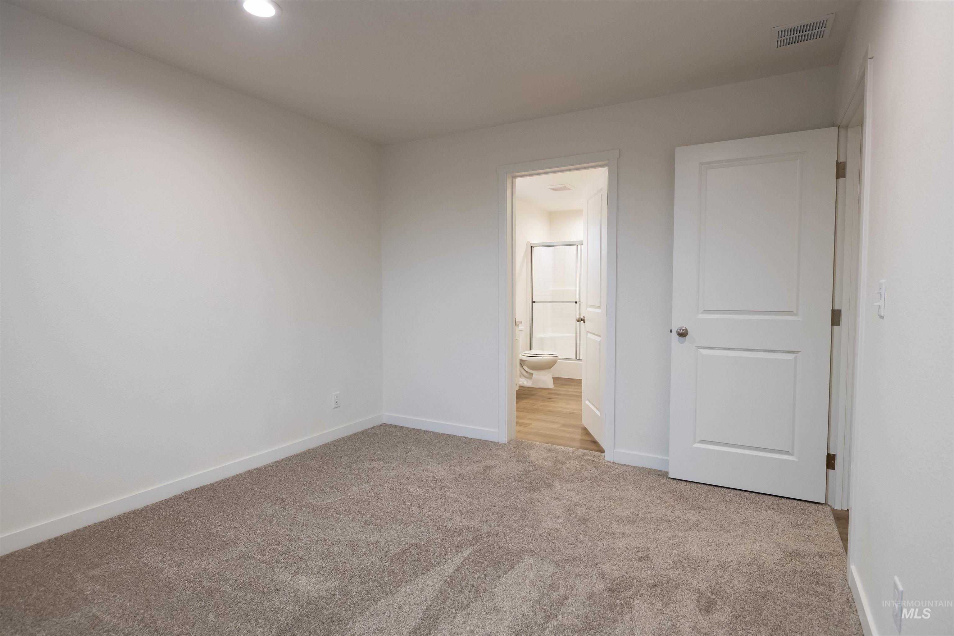 Unfurnished bedroom featuring light colored carpet and ensuite bathroom