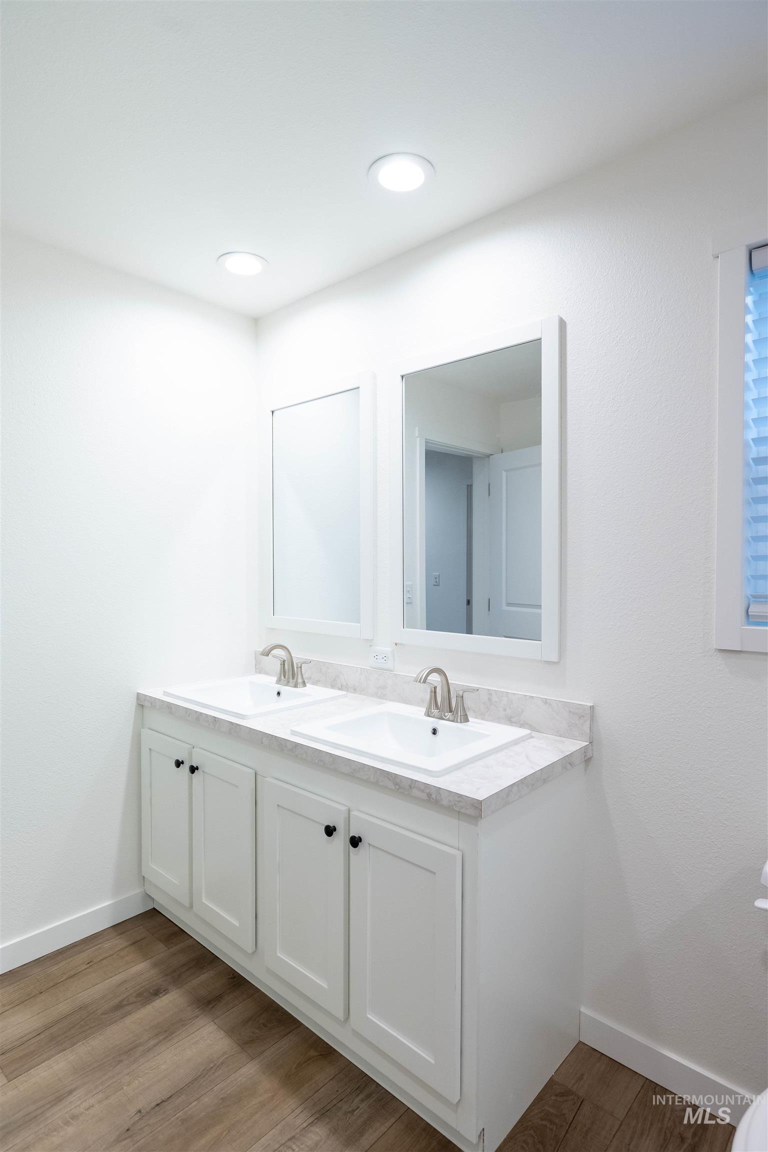 Full bath featuring double vanity and light wood finished floors
