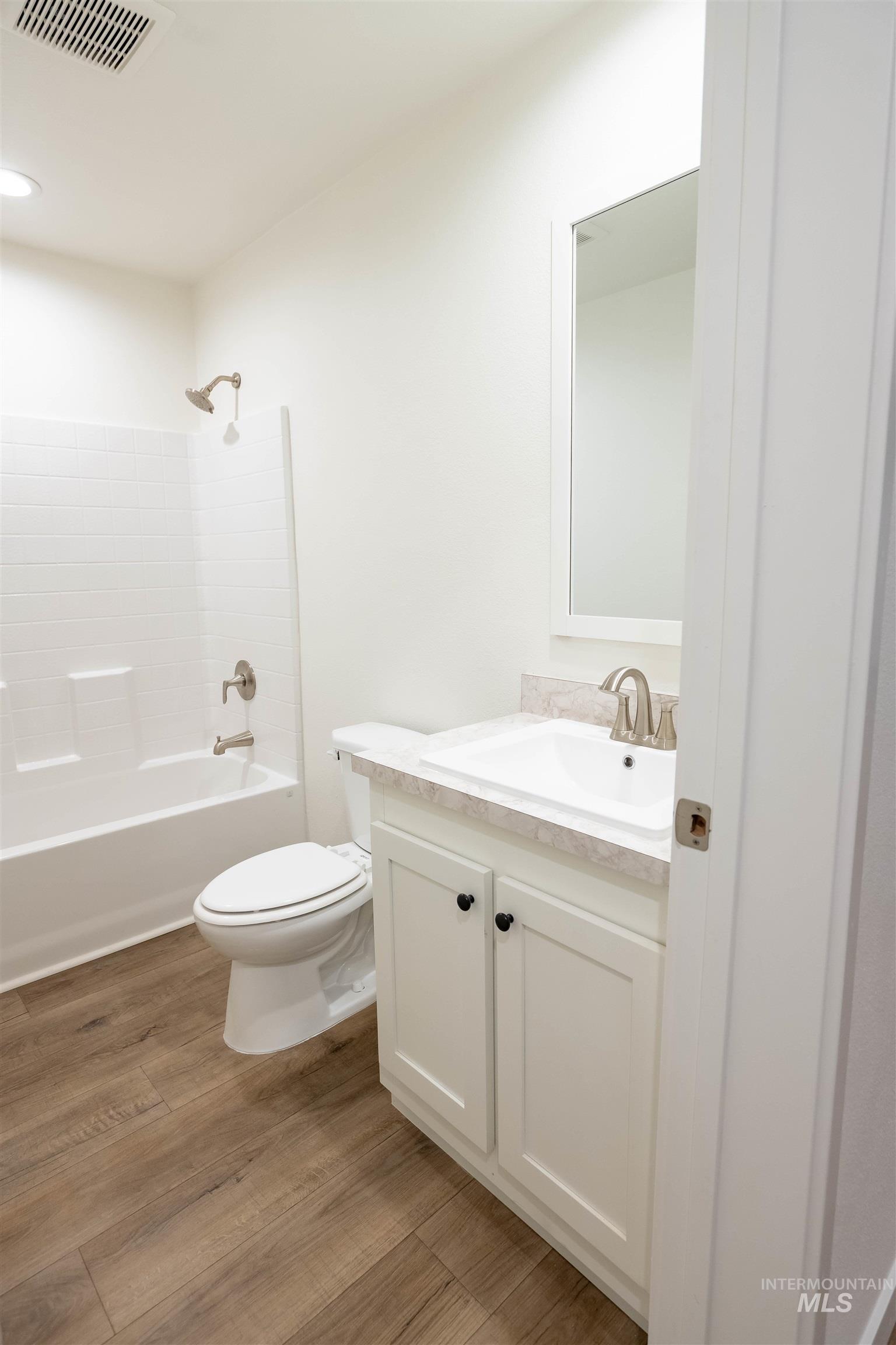 Bathroom featuring vanity, light wood finished floors, and washtub / shower combination