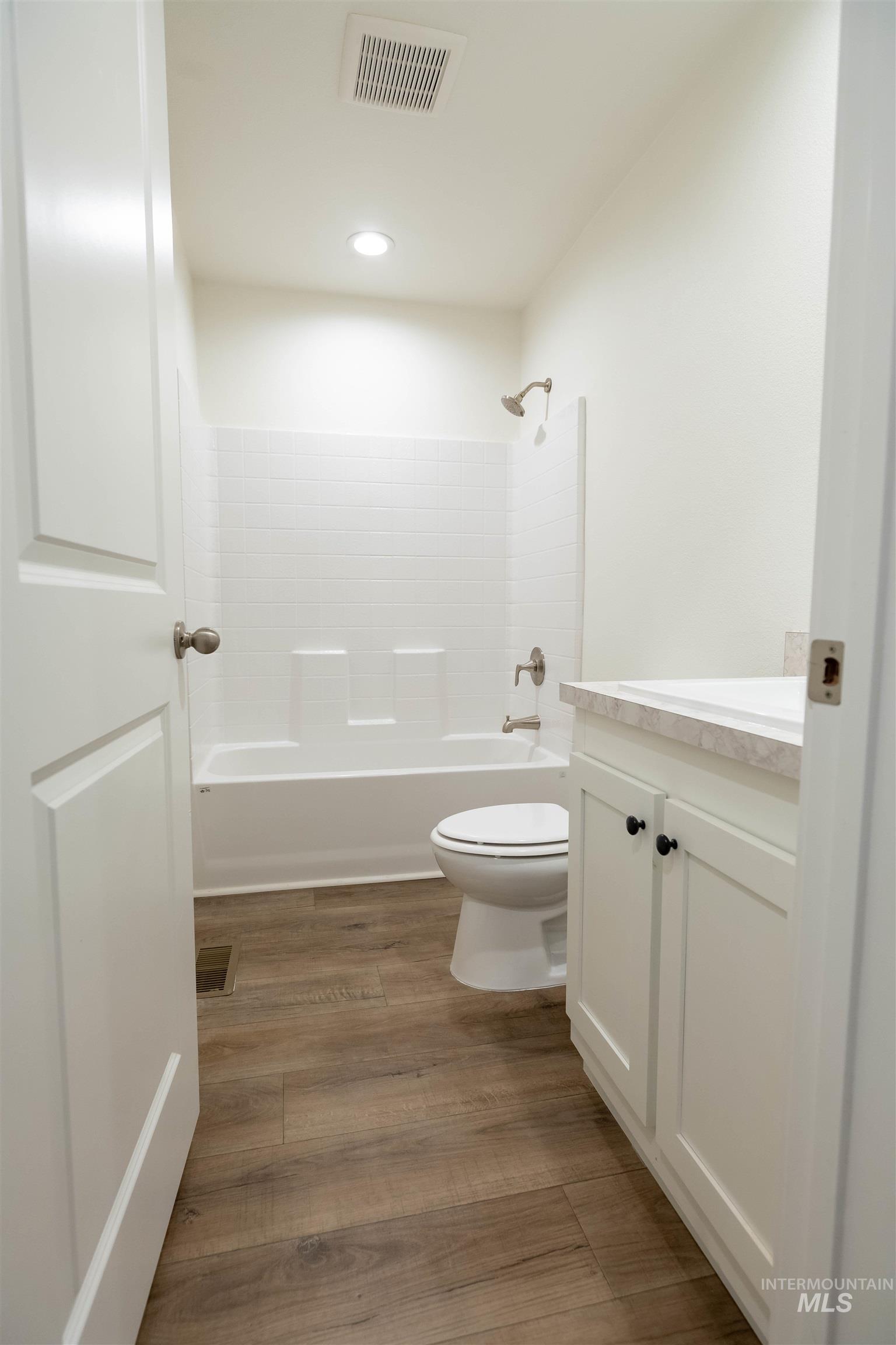 Bathroom with vanity, bathing tub / shower combination, dark wood-style floors, and recessed lighting