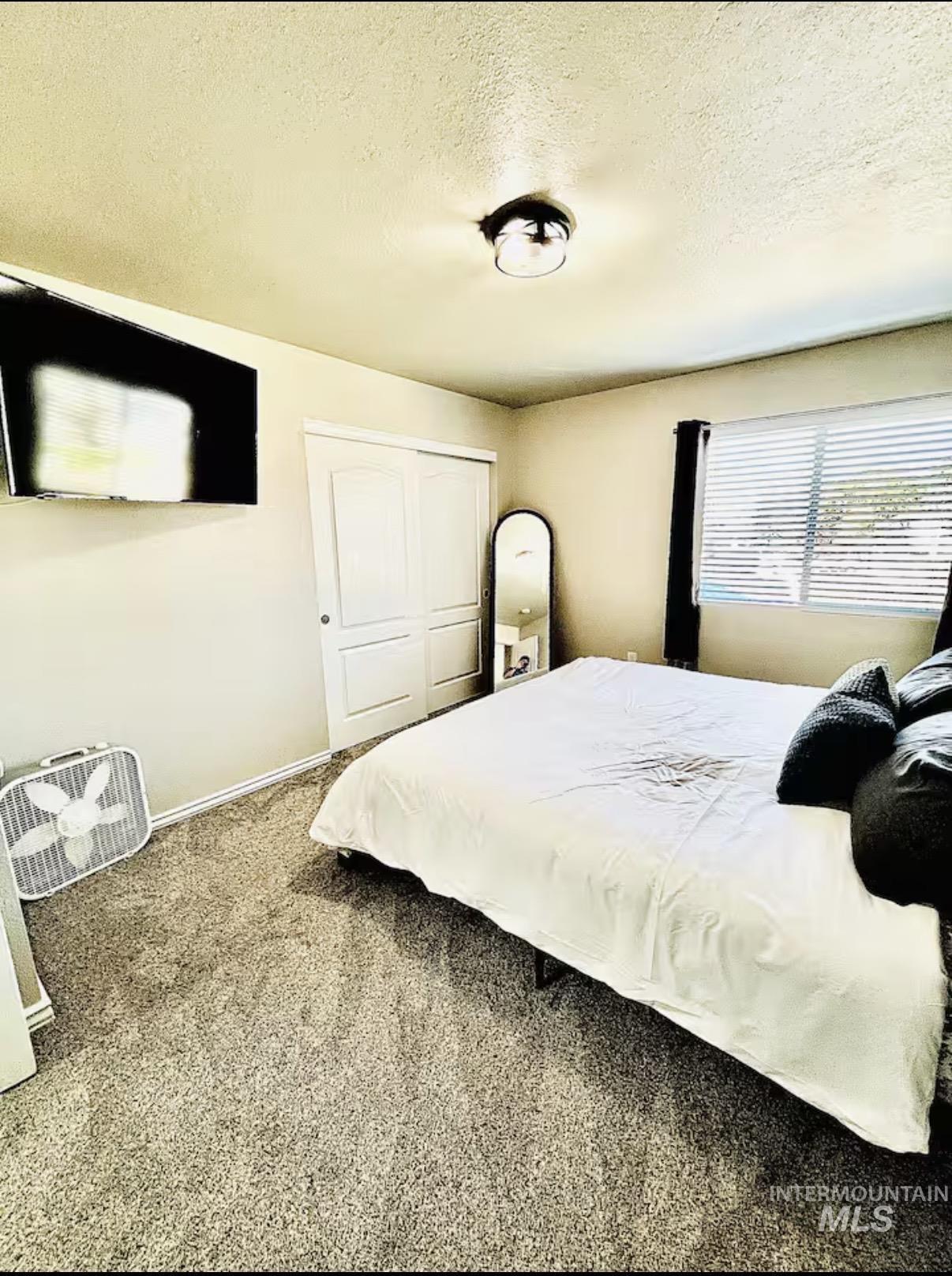 Bedroom with a textured ceiling, carpet floors, and a closet