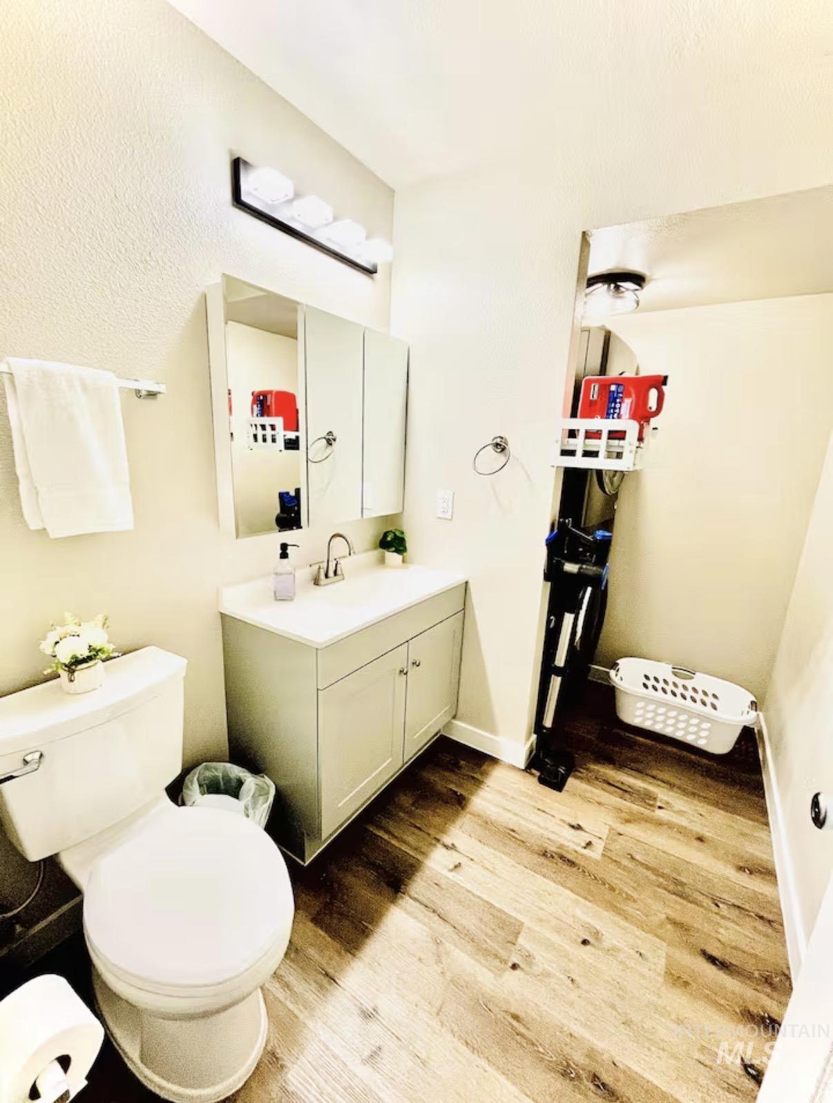 Bathroom with vanity, light wood-style floors, and a textured ceiling