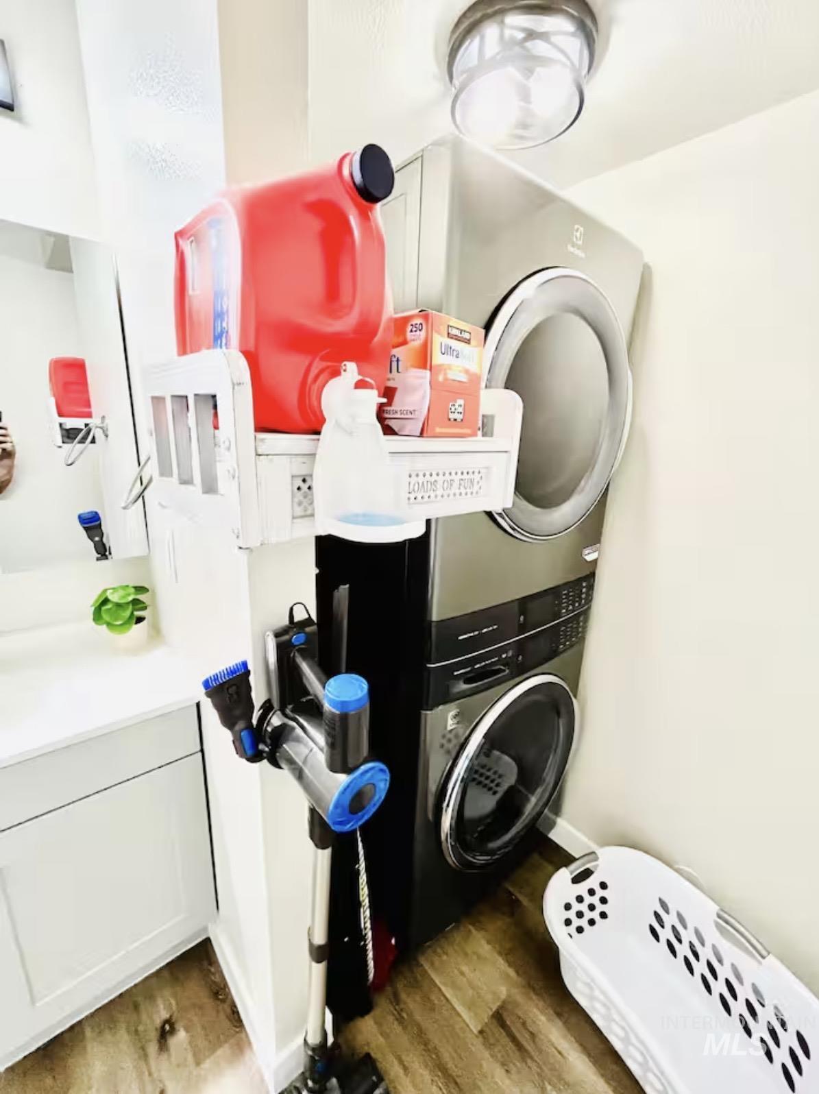Washroom with light wood-style floors and estacked washer and dryer