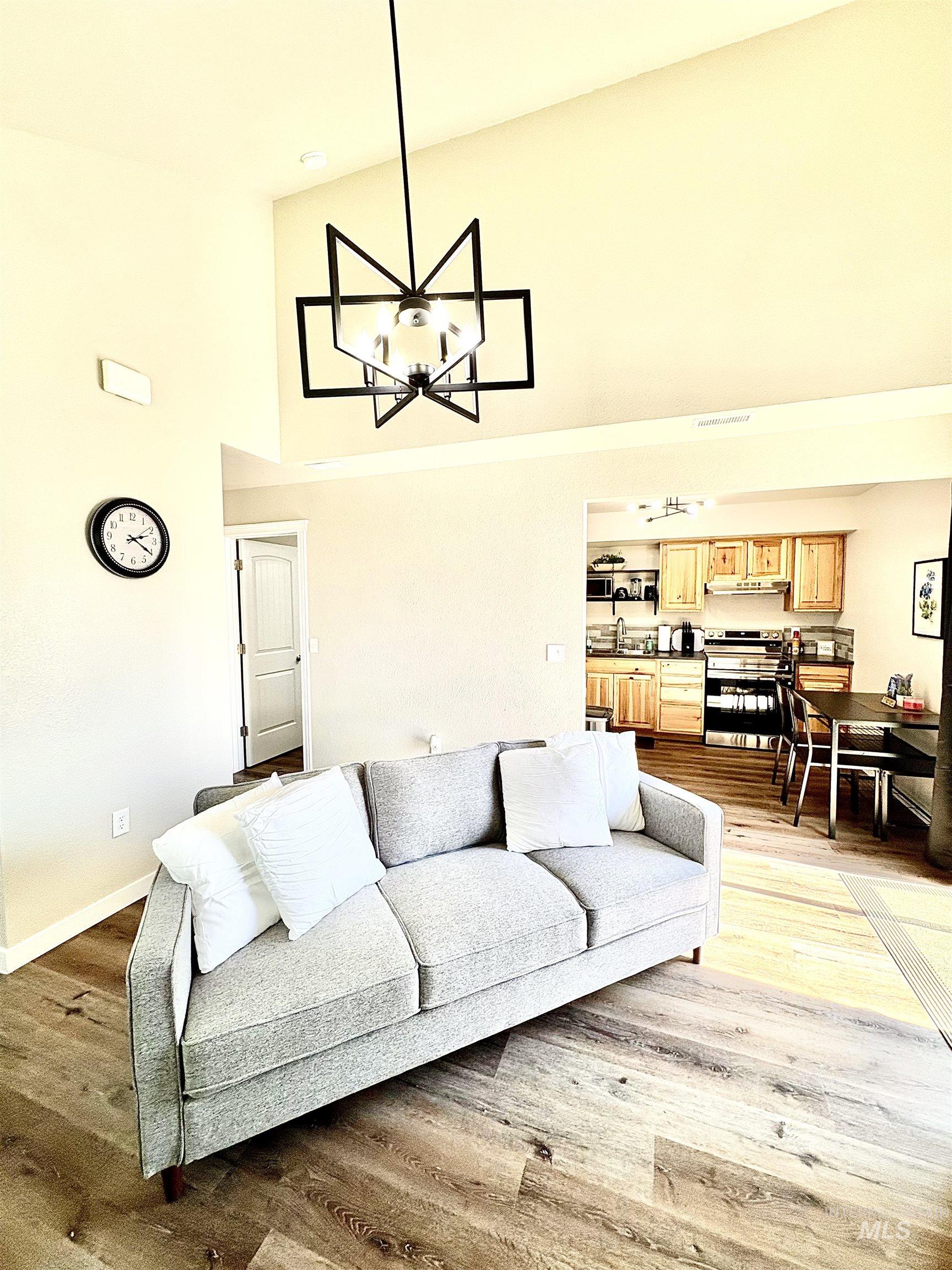 Living room with high vaulted ceiling, a chandelier, and light wood finished floors