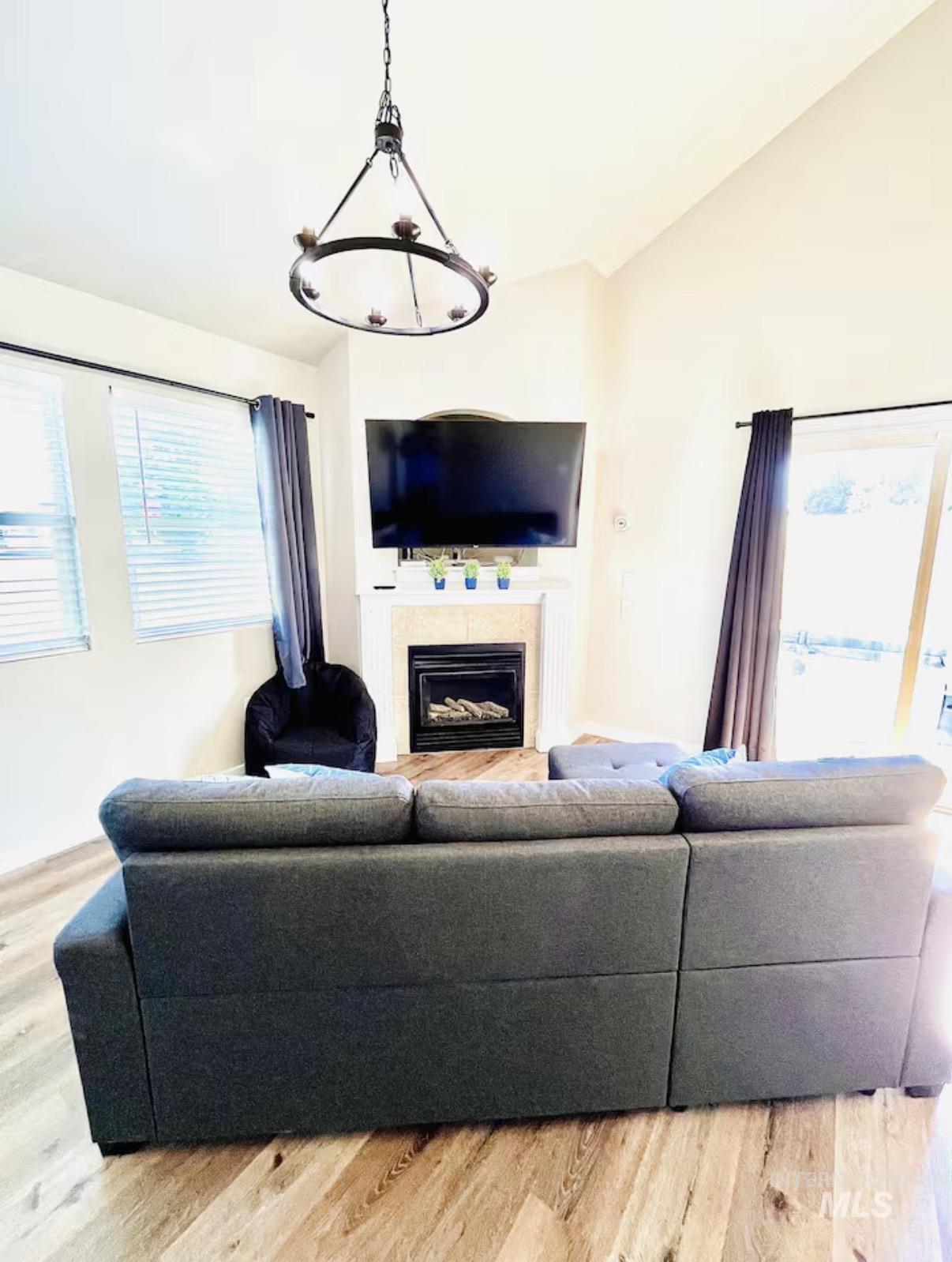 Living area featuring lofted ceiling, a glass covered fireplace, and light wood-style flooring