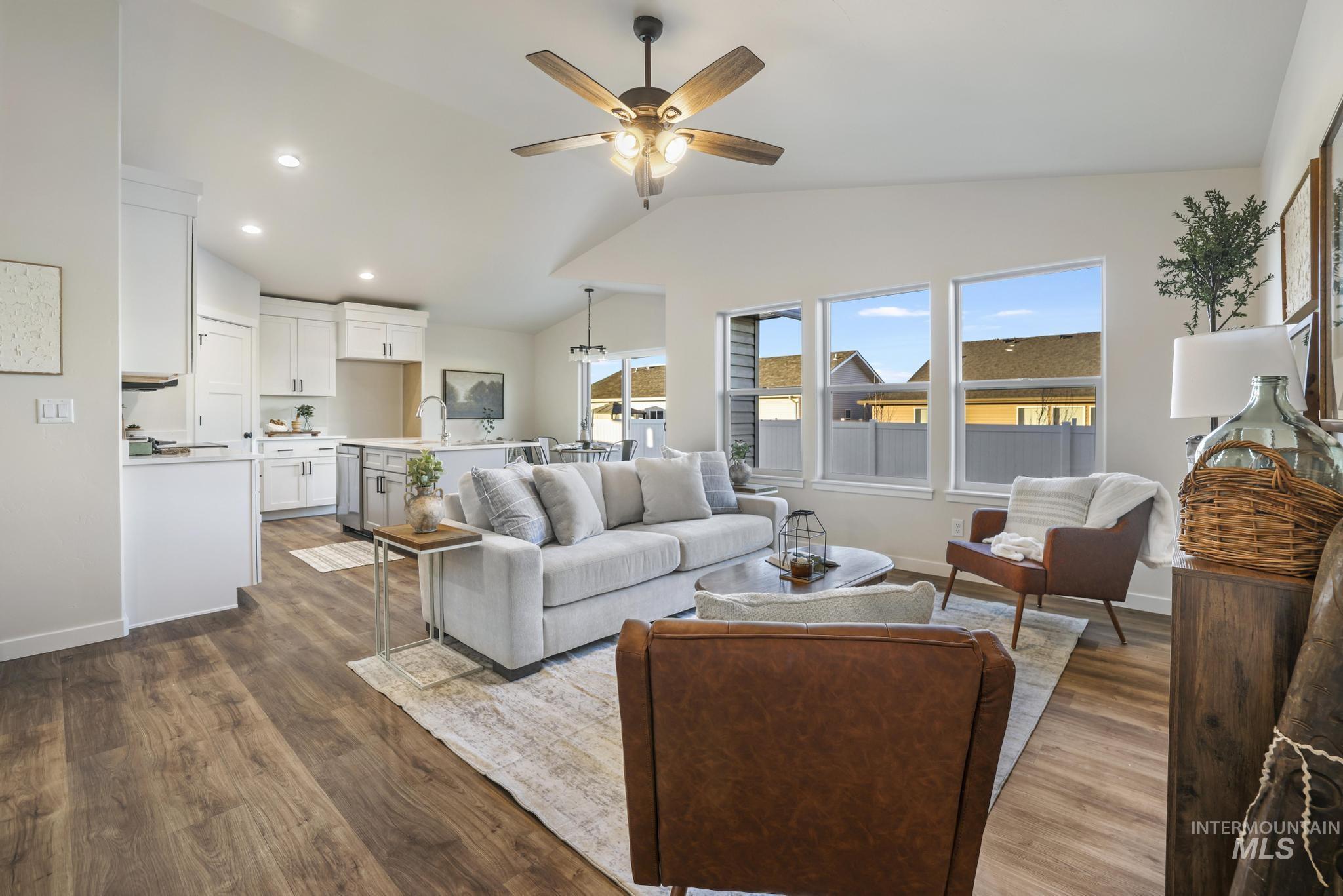 Living area featuring lofted ceiling, ceiling fan, dark wood-type flooring, and recessed lighting
