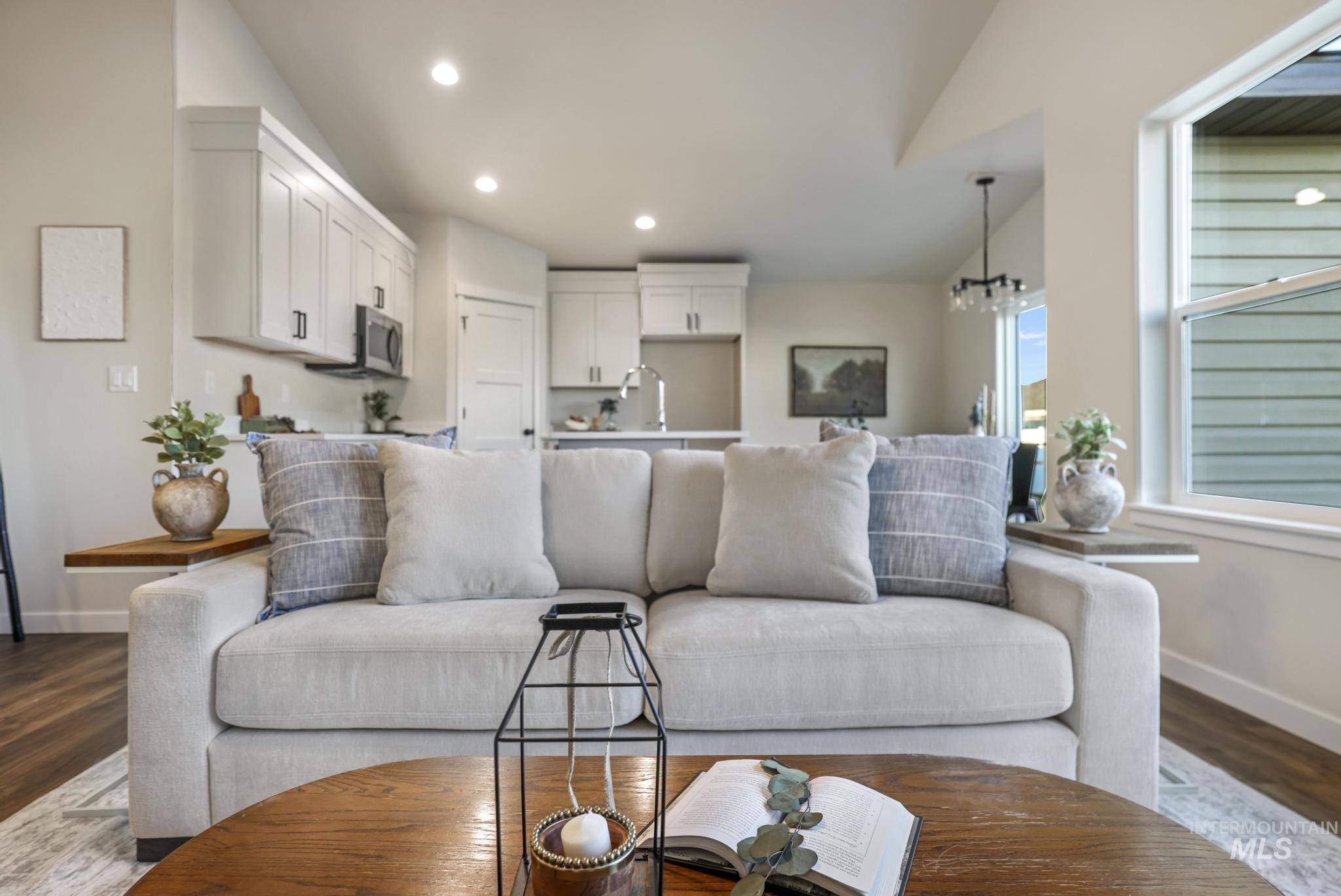 Living area featuring dark wood-style flooring, vaulted ceiling, recessed lighting, and a chandelier