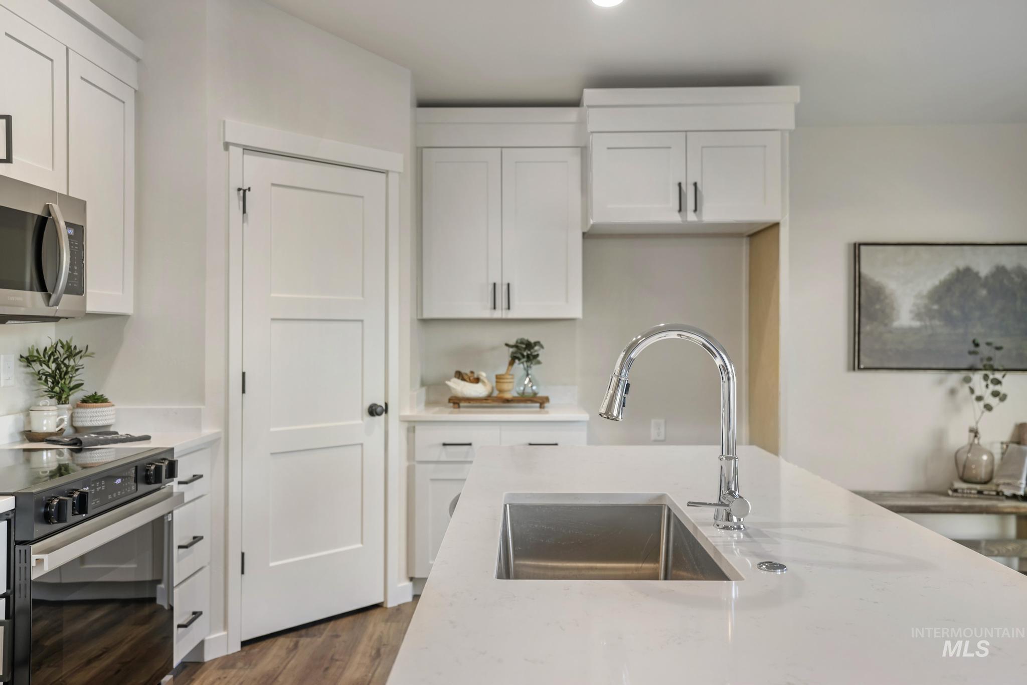 Kitchen with light stone counters, stainless steel microwave, black electric range, and white cabinets