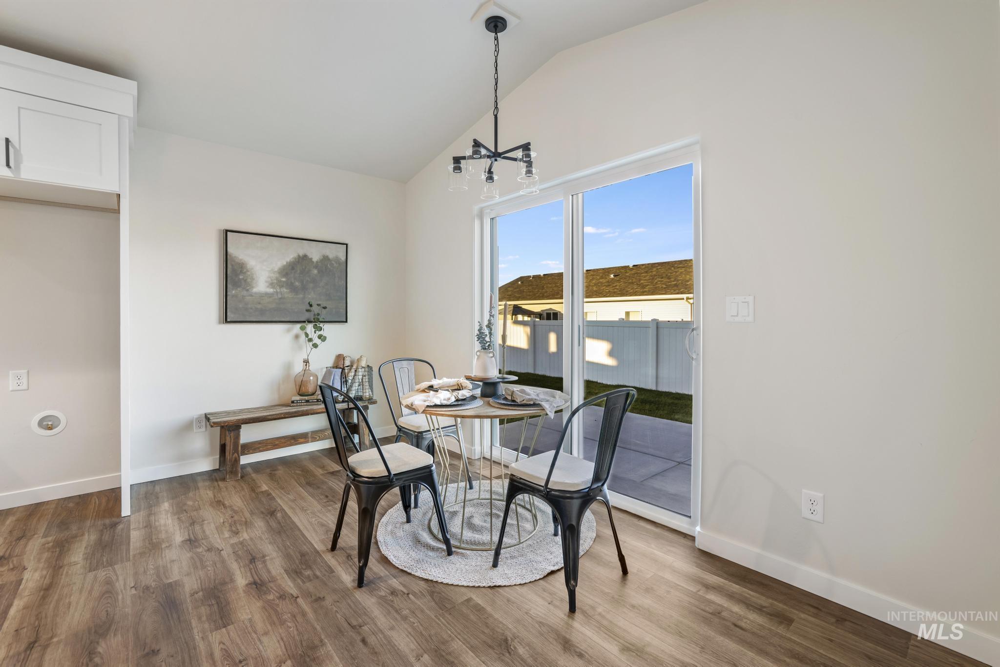 Dining space featuring lofted ceiling, wood finished floors, and a chandelier
