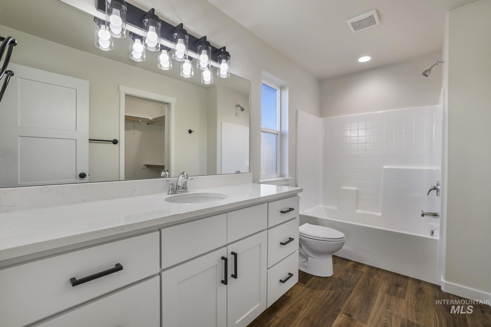 Full bath with vanity, bathing tub / shower combination, dark wood-type flooring, and a walk in closet