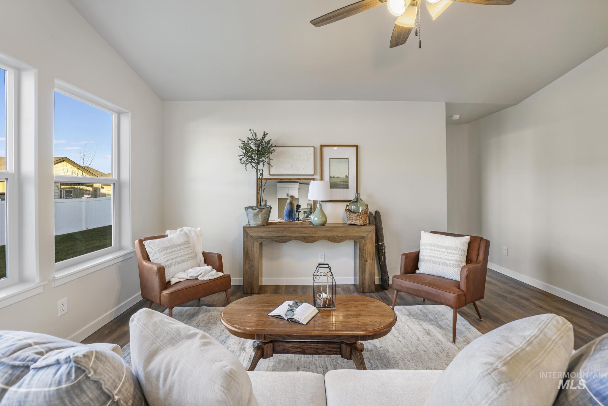 Living area featuring a ceiling fan, wood finished floors, and vaulted ceiling