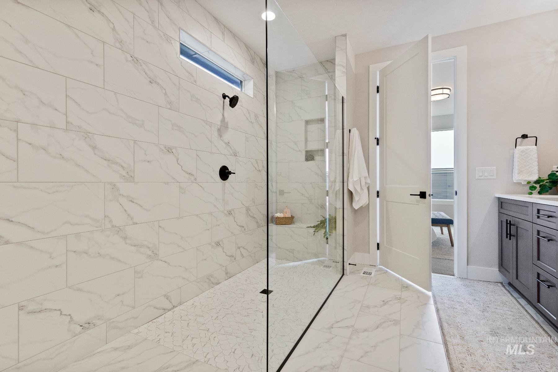Bathroom featuring ensuite bathroom, vanity, a marble finish shower, and light marble finish floors