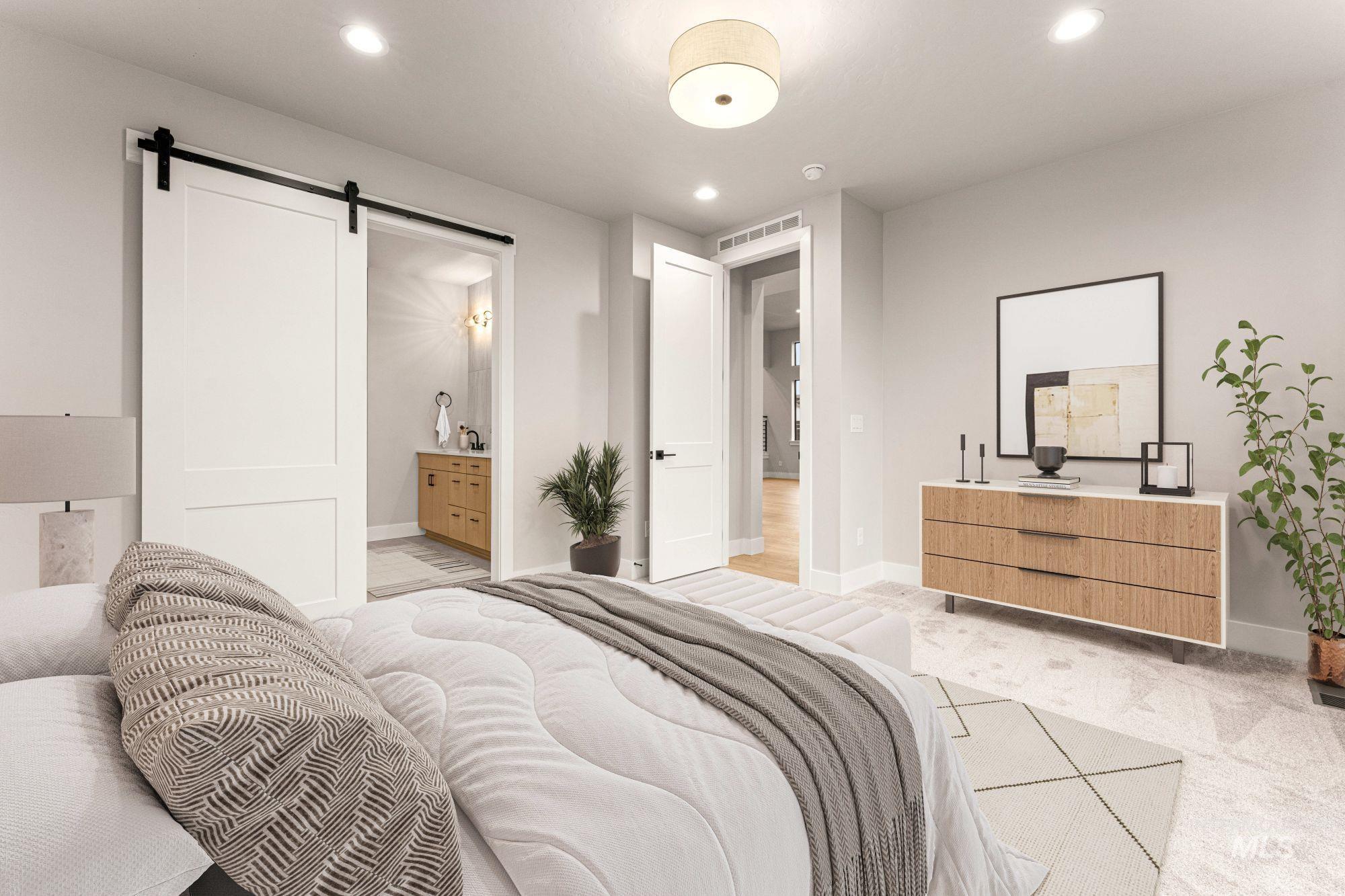 Bedroom featuring a barn door, recessed lighting, ensuite bath, and light colored carpet