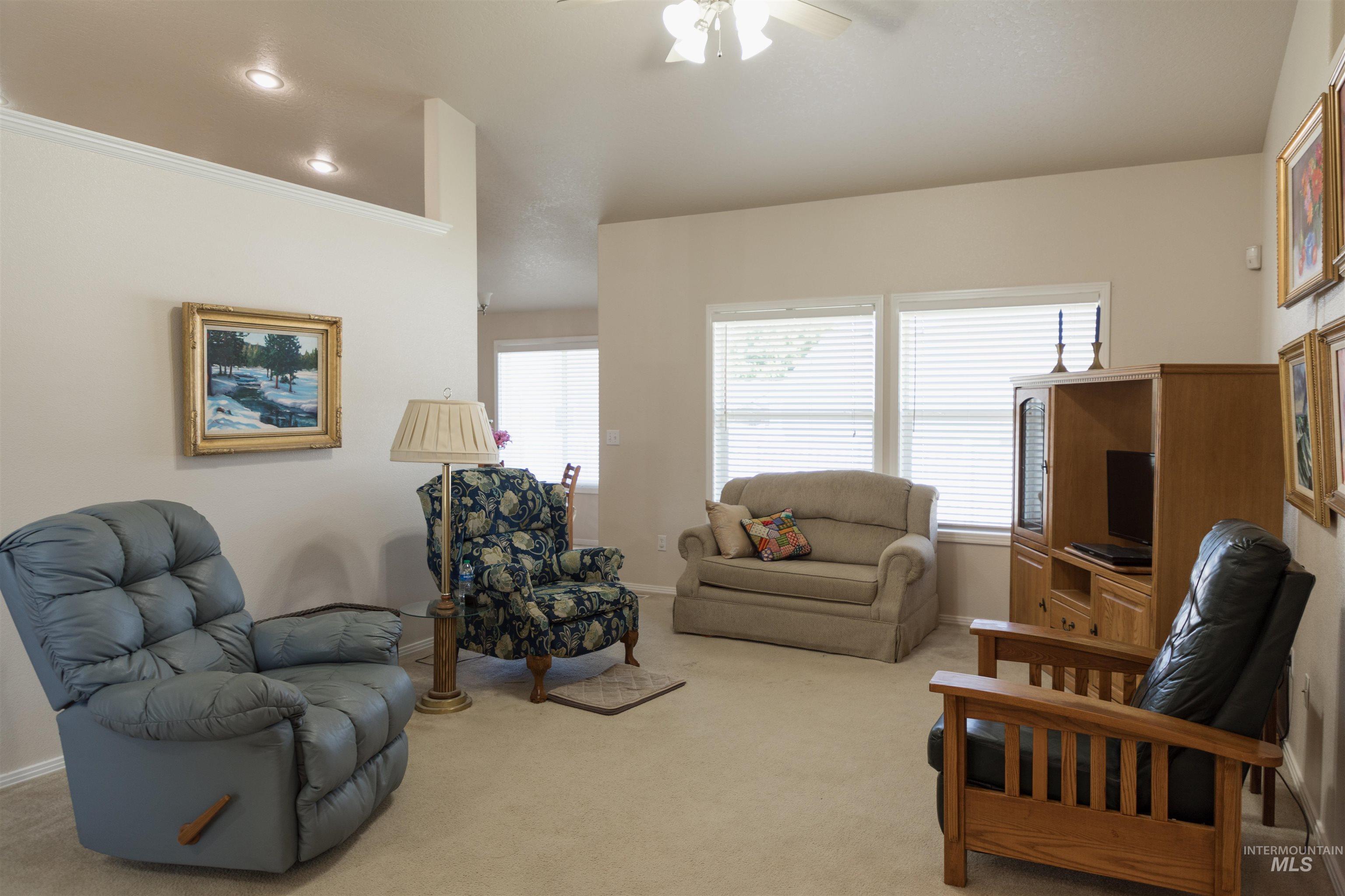 Living area with a ceiling fan, light carpet, crown molding, and recessed lighting