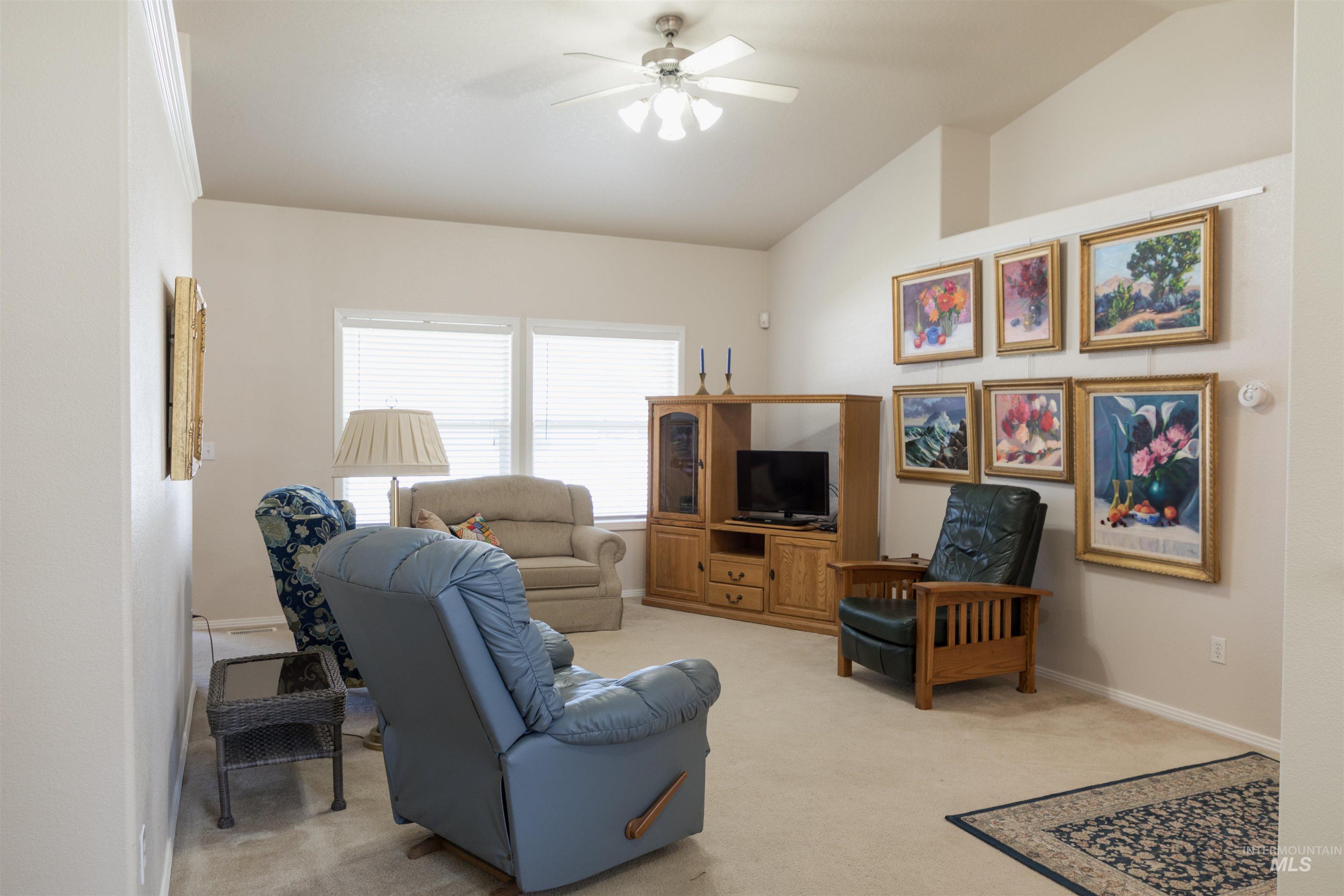 Living room with vaulted ceiling, light carpet, and a ceiling fan