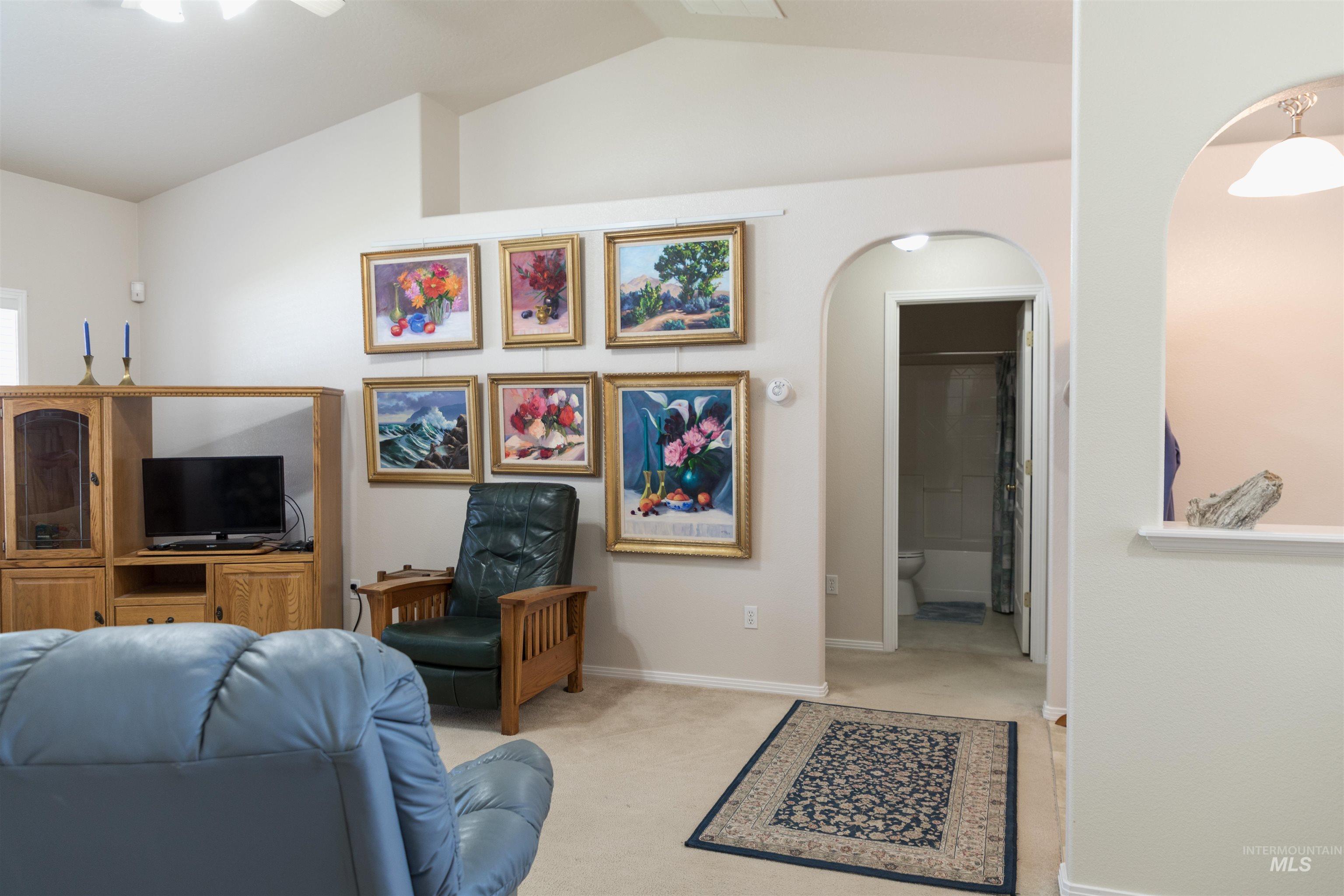 Living room featuring vaulted ceiling, carpet floors, and arched walkways