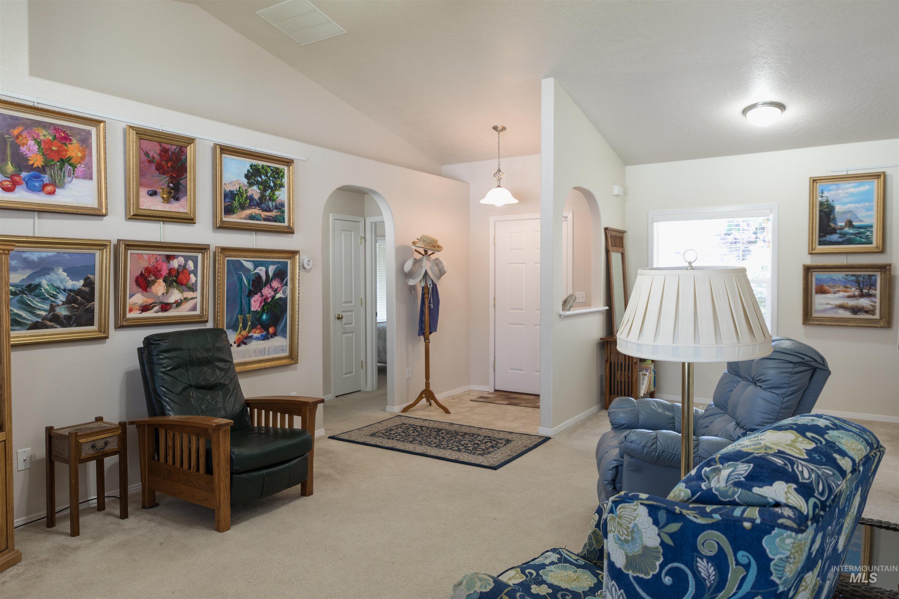 Living room with arched walkways, carpet, and vaulted ceiling