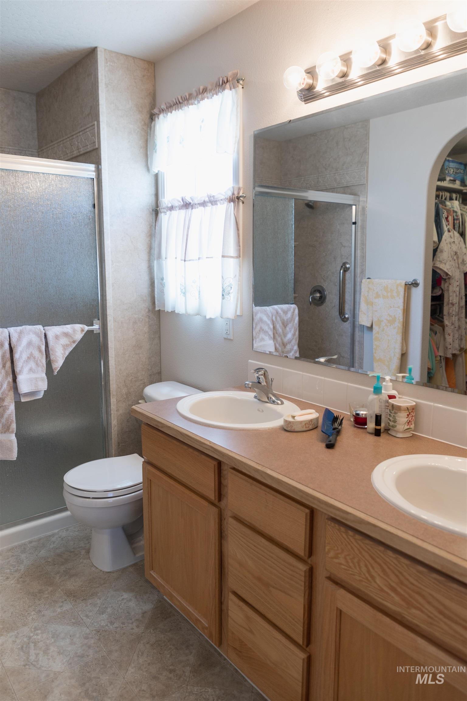Full bathroom with double vanity, a walk in closet, and a shower stall