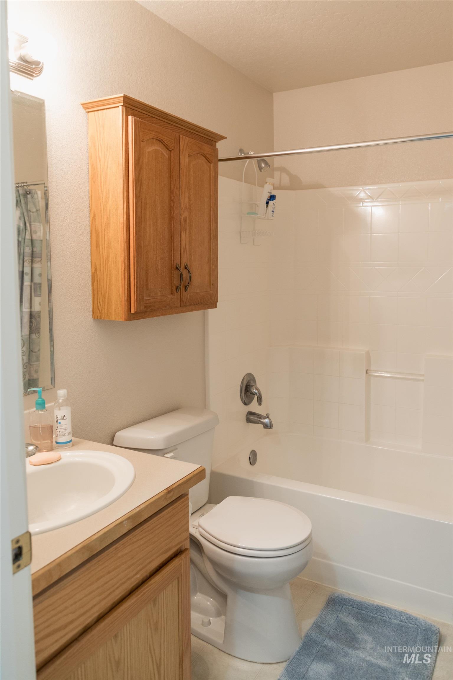 Full bath featuring vanity, shower / tub combo with curtain, and light tile patterned floors