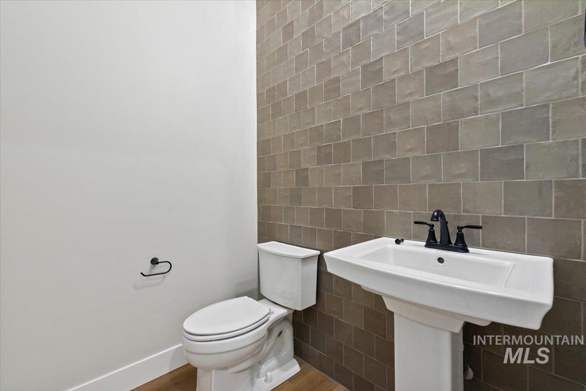 Half bathroom with tile walls and wood finished floors