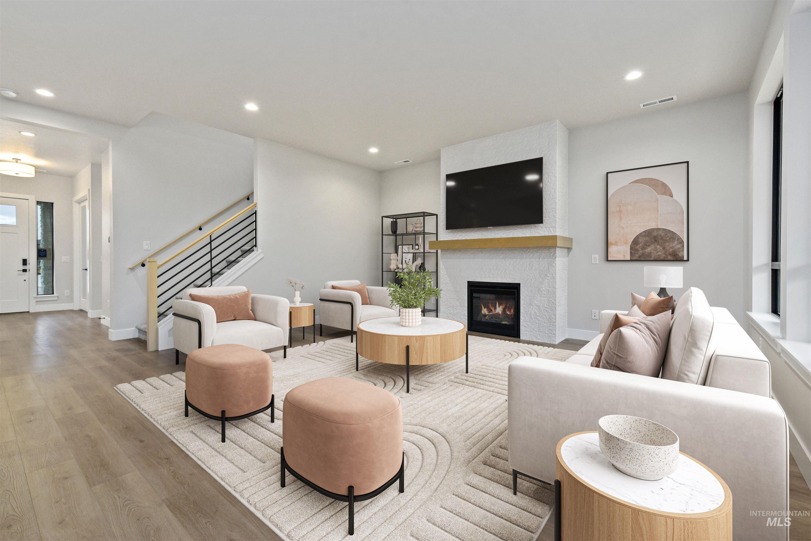 Living room featuring wood finished floors, recessed lighting, a glass covered fireplace, and stairway