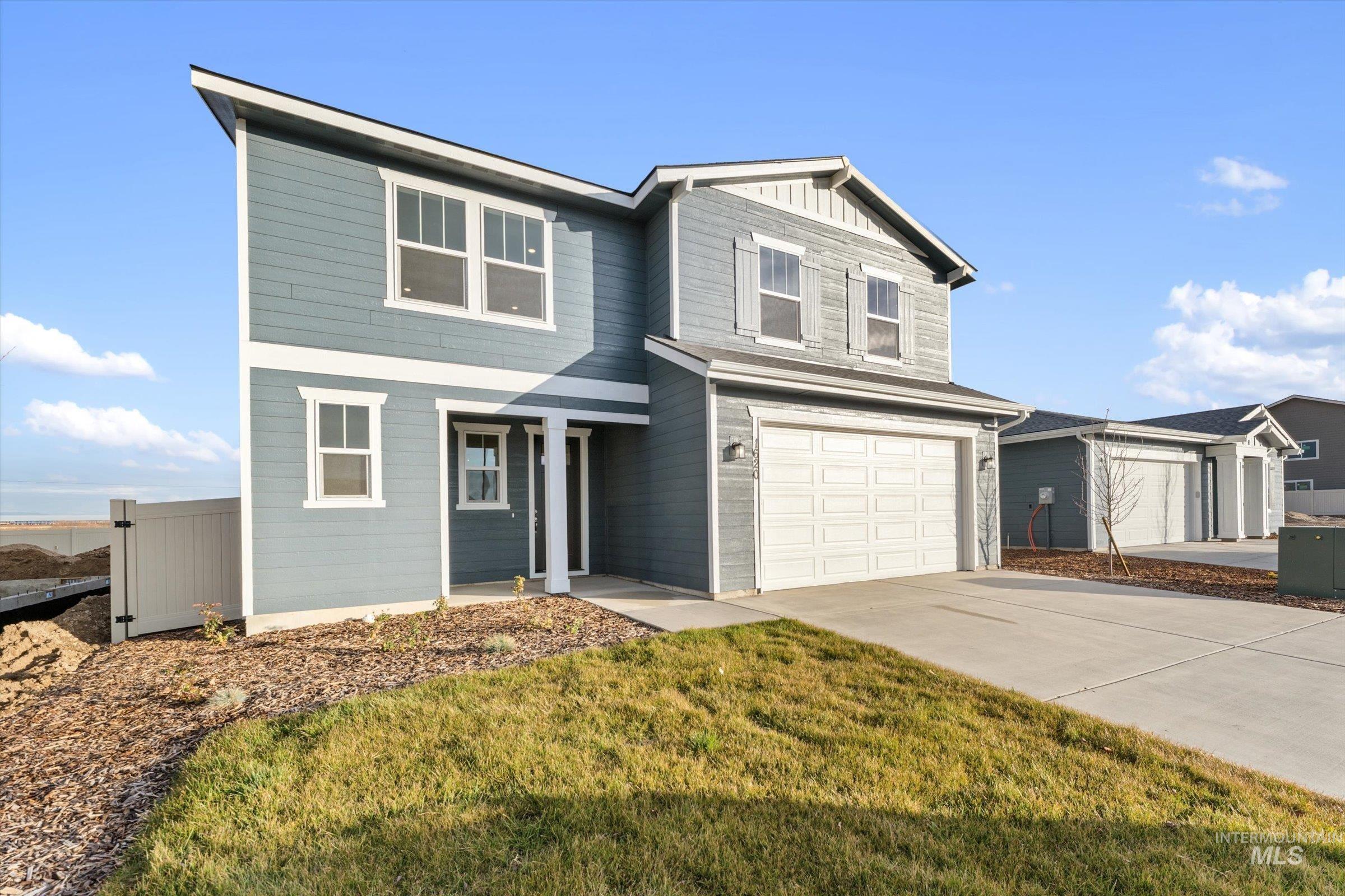 View of front facade featuring board and batten siding, driveway, and a garage