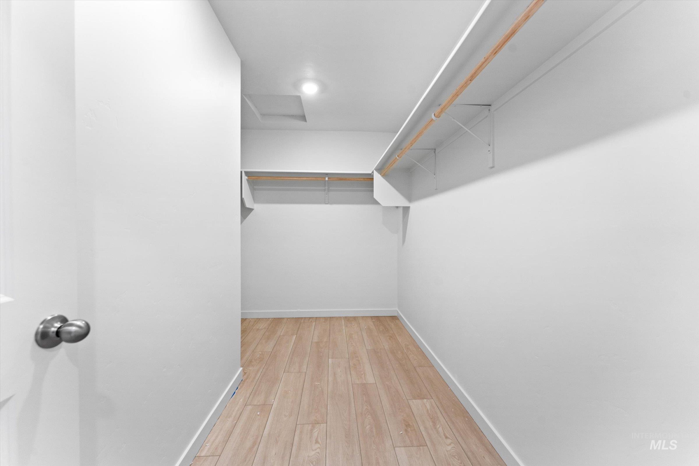 Walk in closet featuring light wood-style floors and attic access