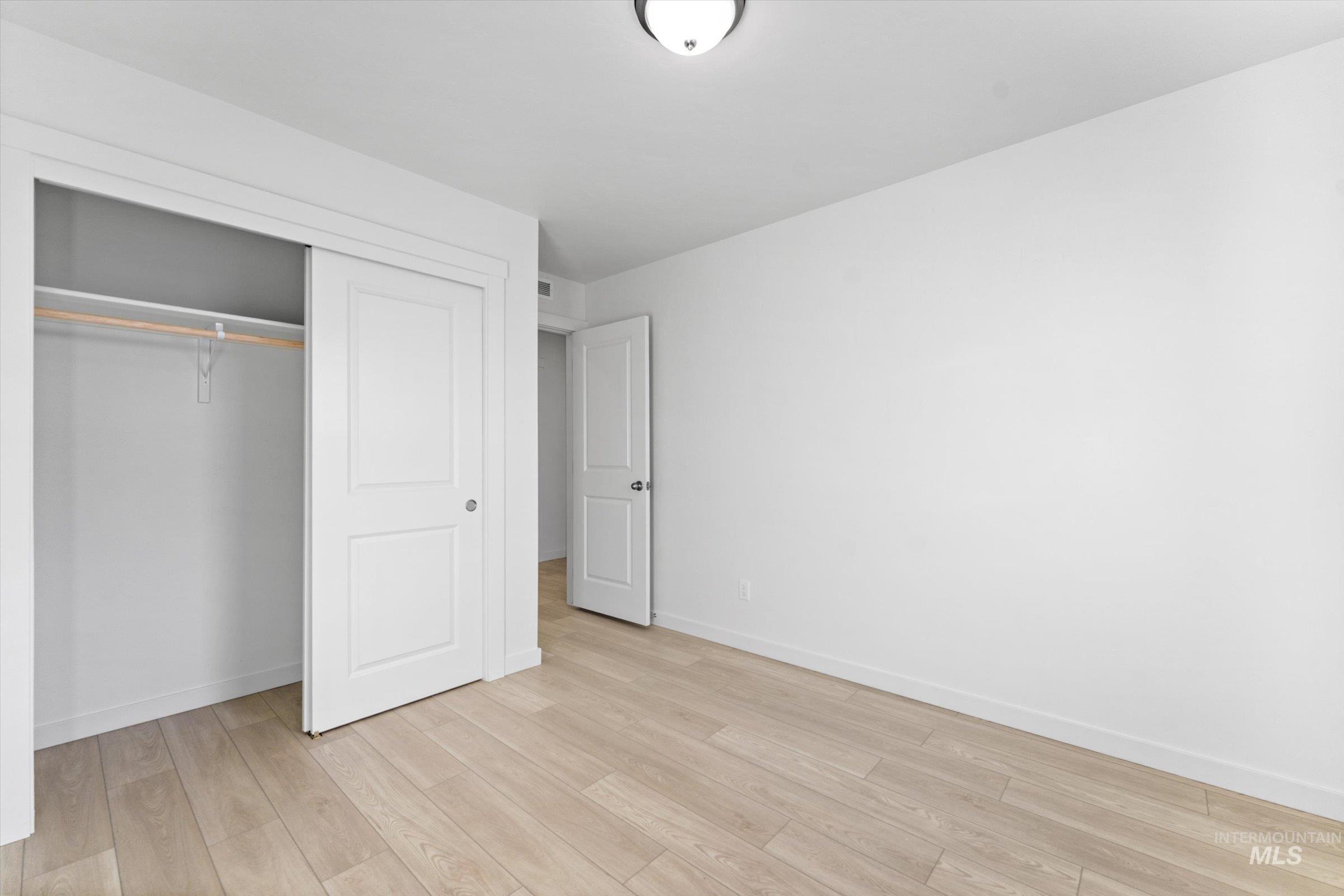 Unfurnished bedroom featuring light wood-style floors and a closet