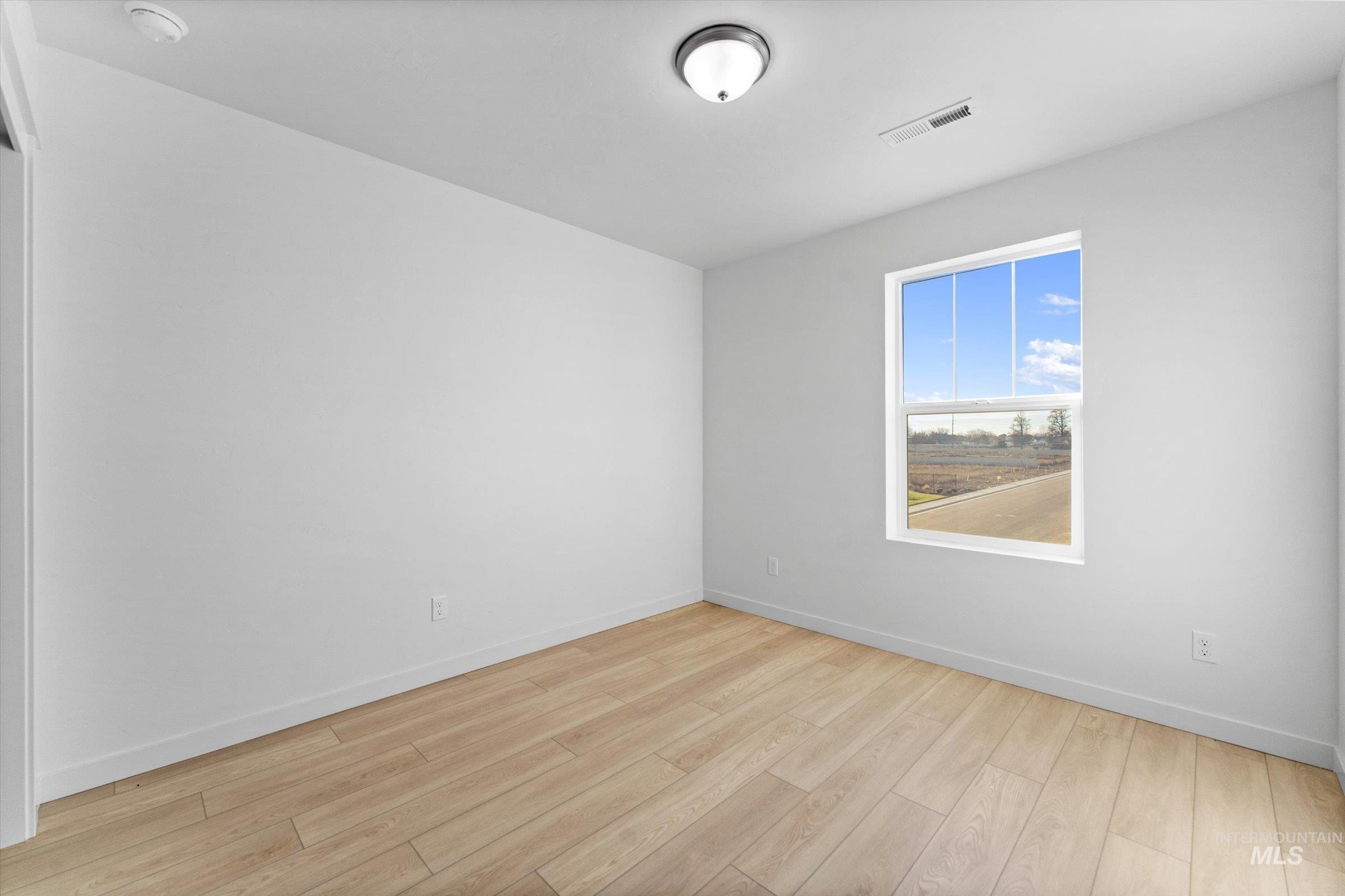 Empty room with light wood-type flooring and baseboards