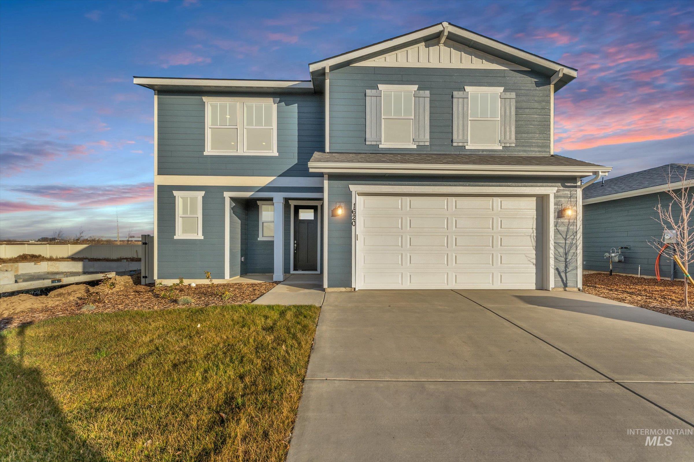 View of front facade featuring driveway, a garage, and a lawn