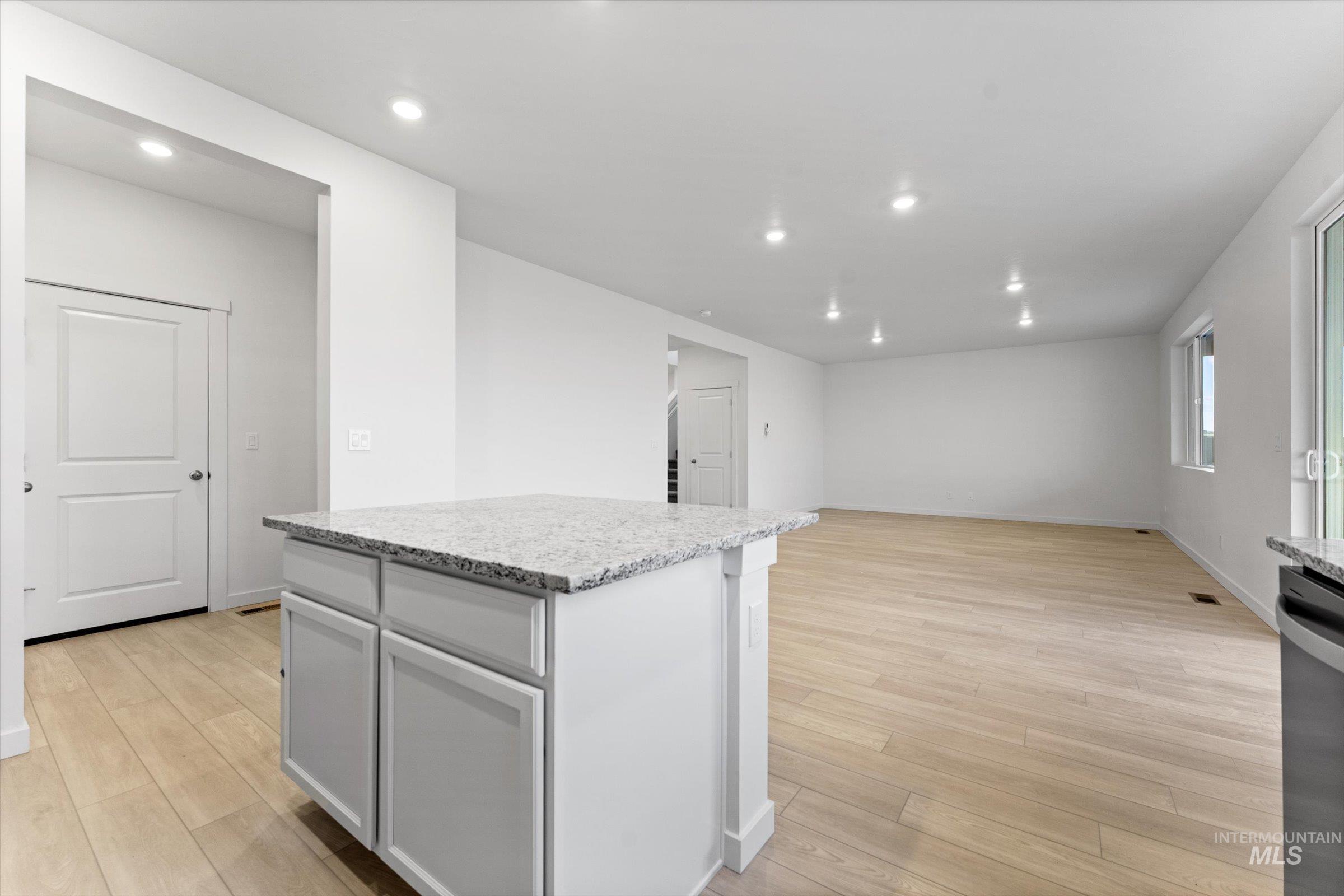 Kitchen featuring recessed lighting, a center island, light stone counters, dishwasher, and light wood finished floors